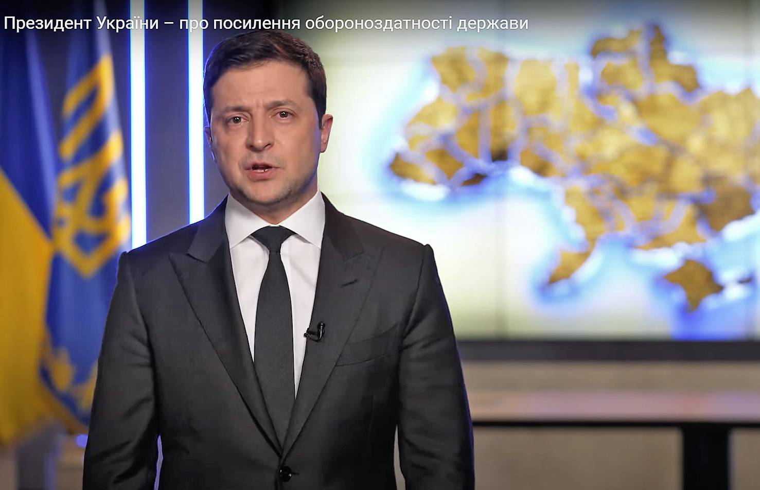 Prezydent Zełenski wygłasza orędziem na tle wielkiej mapy Ukrainy
