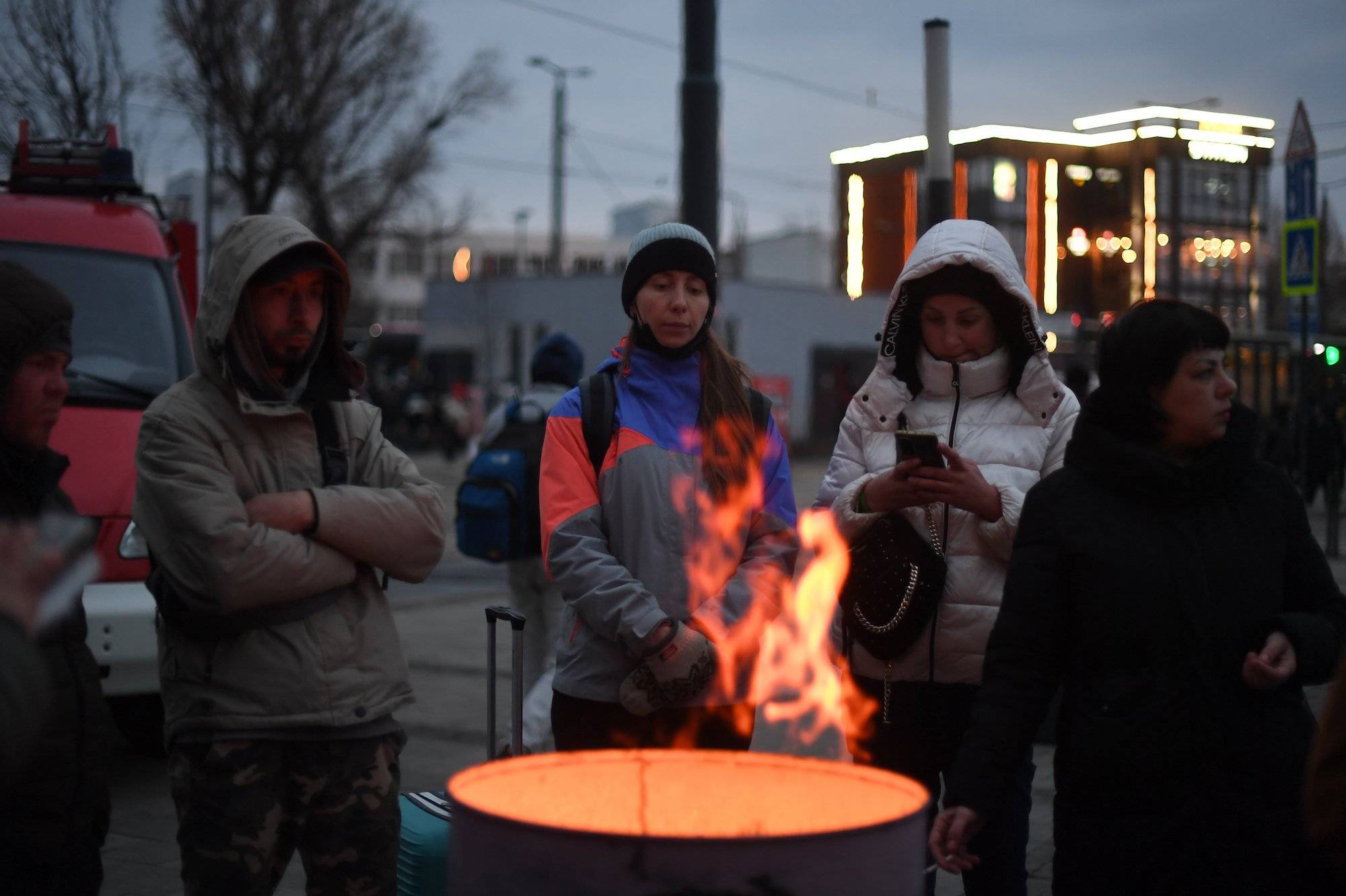 Refugees warm up around a bonfire outside the Lviv train station, western Ukraine, on March 03, 2022. - Ukraine and Russia agreed to create humanitarian corridors to evacuate civilians on March 03 in a second round of talks since Moscow invaded last week, a top Ukrainian official said. (Photo by