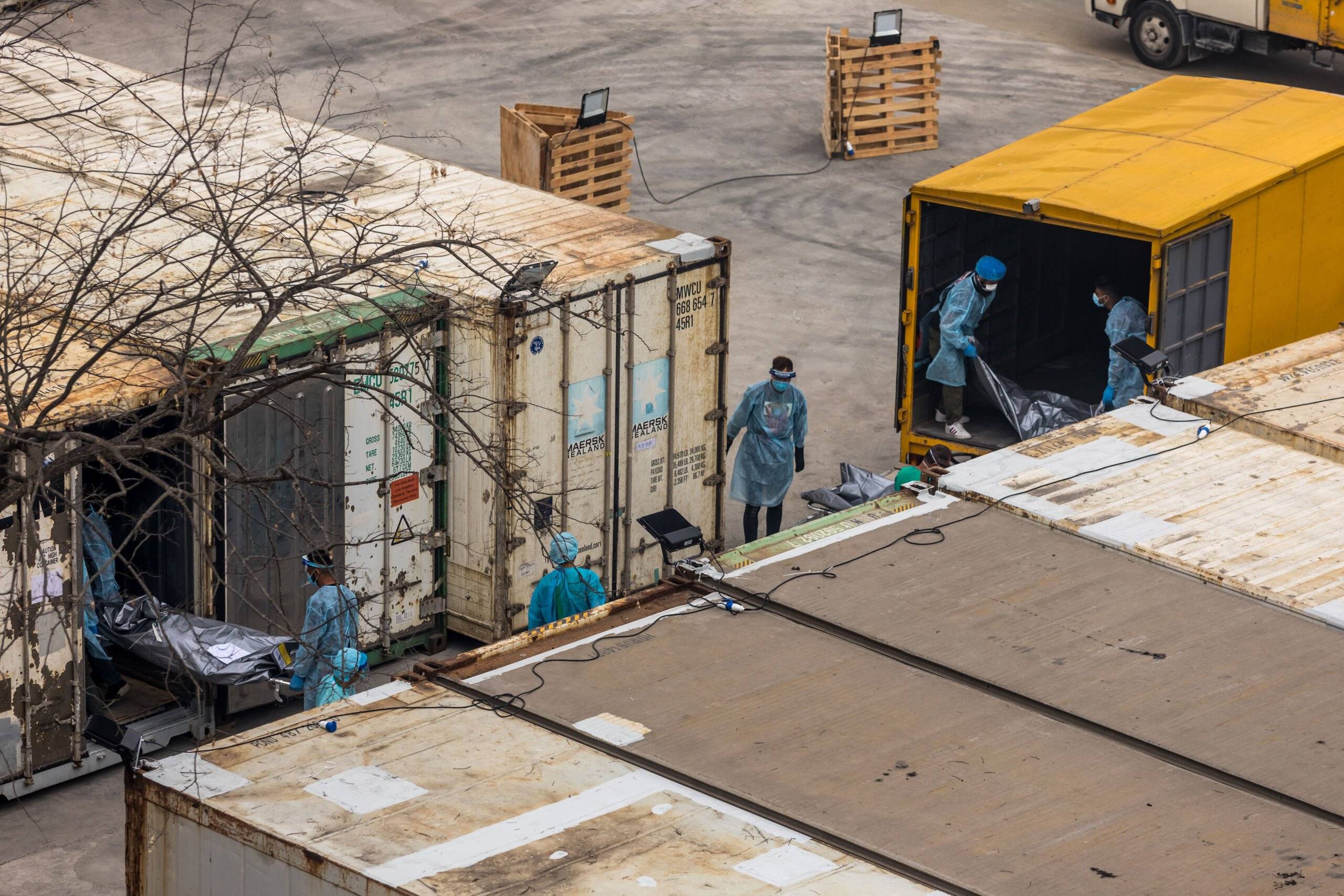Pracownicy wnoszą ciała do tymczasowych kostnic w kontenerach w Hong Kongu
