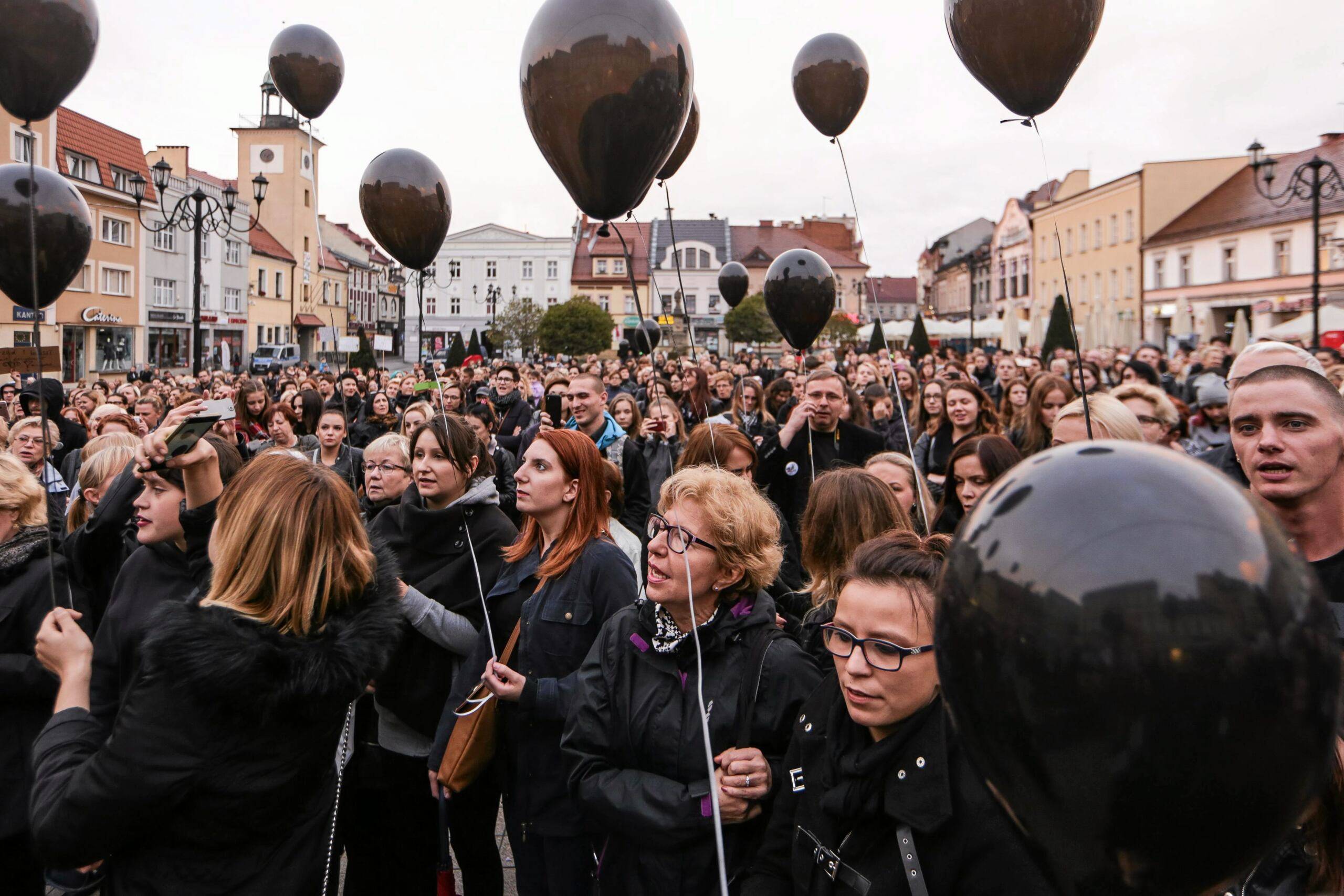 Kobiety zgromadzone na rynku trzymają czarne balony