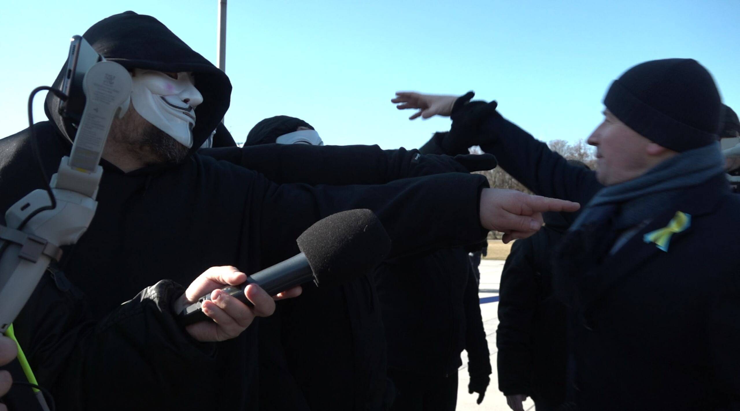 Bartłomiej Wróblewski wyciąga rękę, żeby zdjąć maskę aktywistce