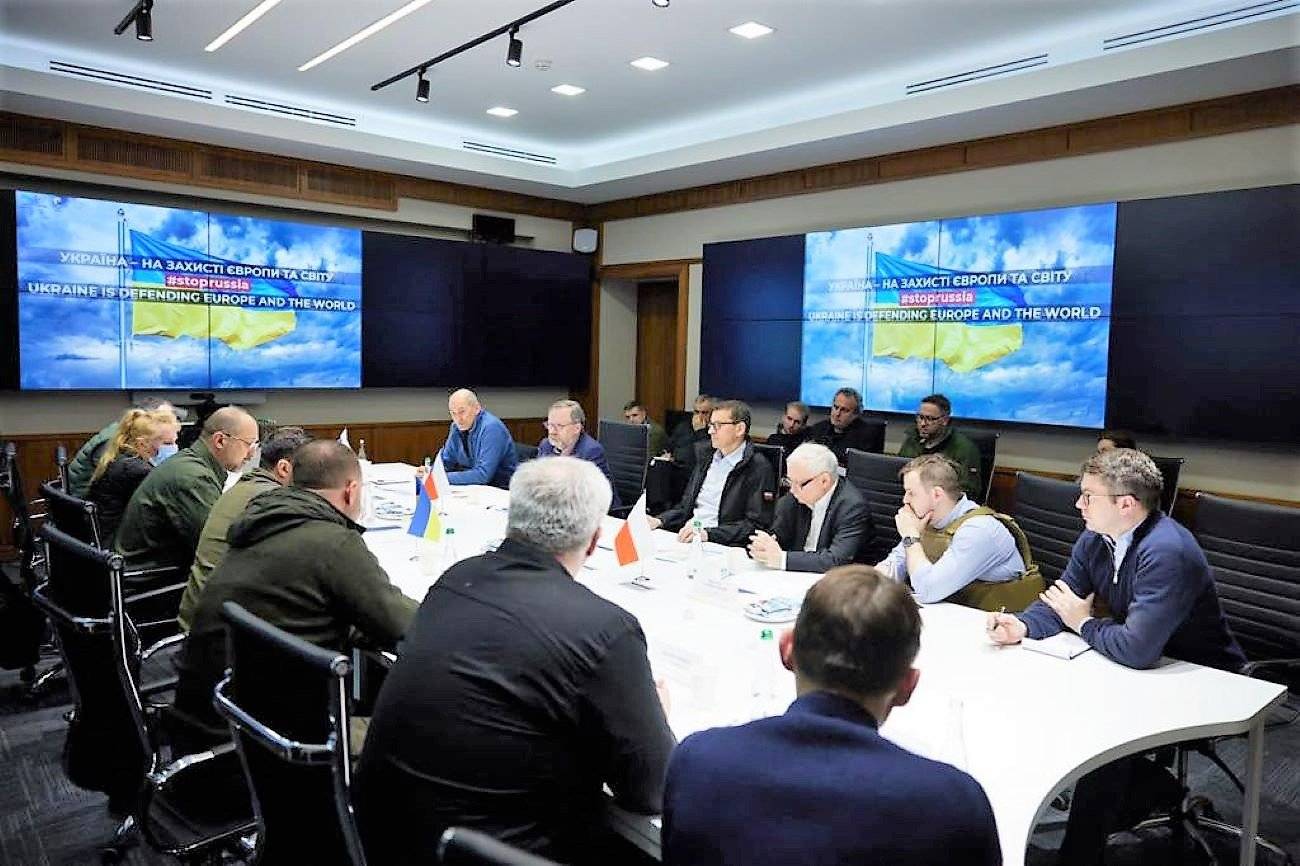 Przy długim stole w pomieszczeniu z ekranami na ścianach siedza ludzie, wizyta trzech premierów u prezydenta Ukrainy Zełenskiego