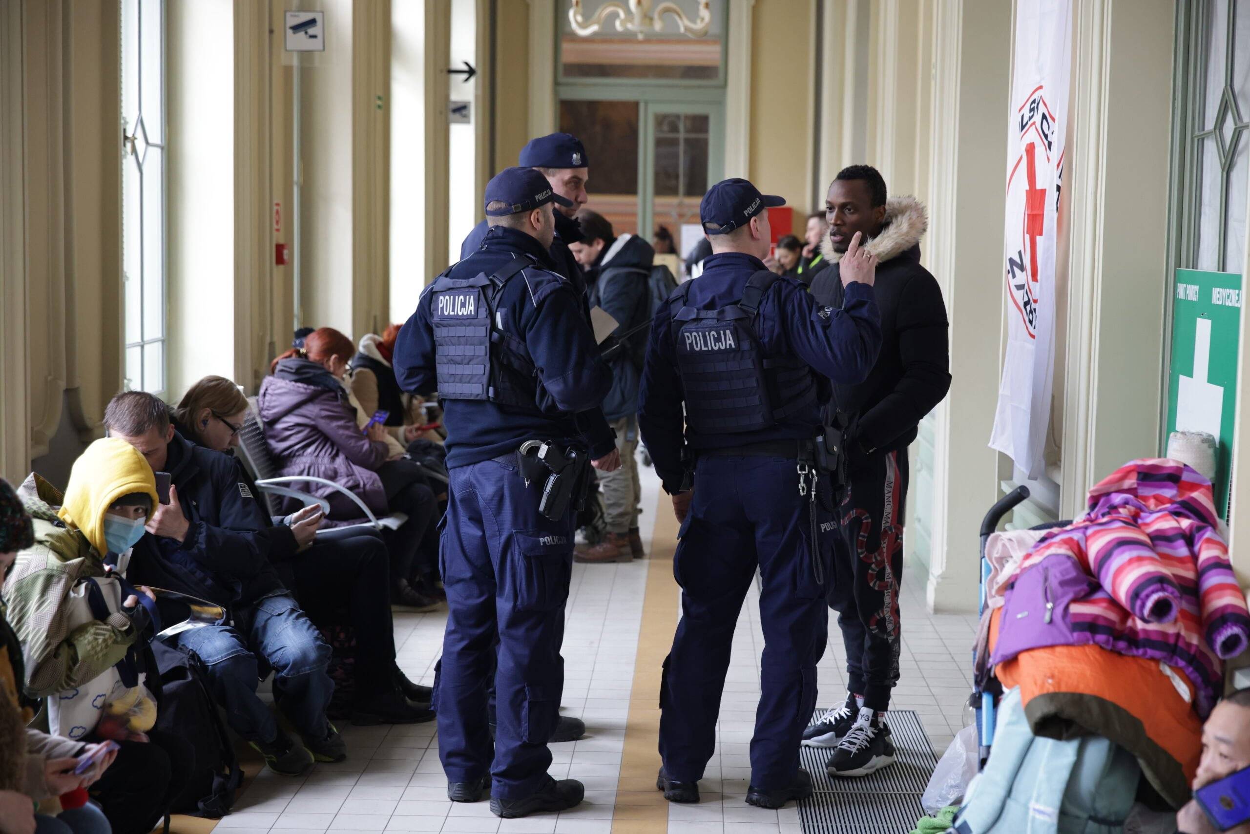 Policjanci rozmawiają z ciemnoskórym mężczyzną w hali dworca w Przemyślu