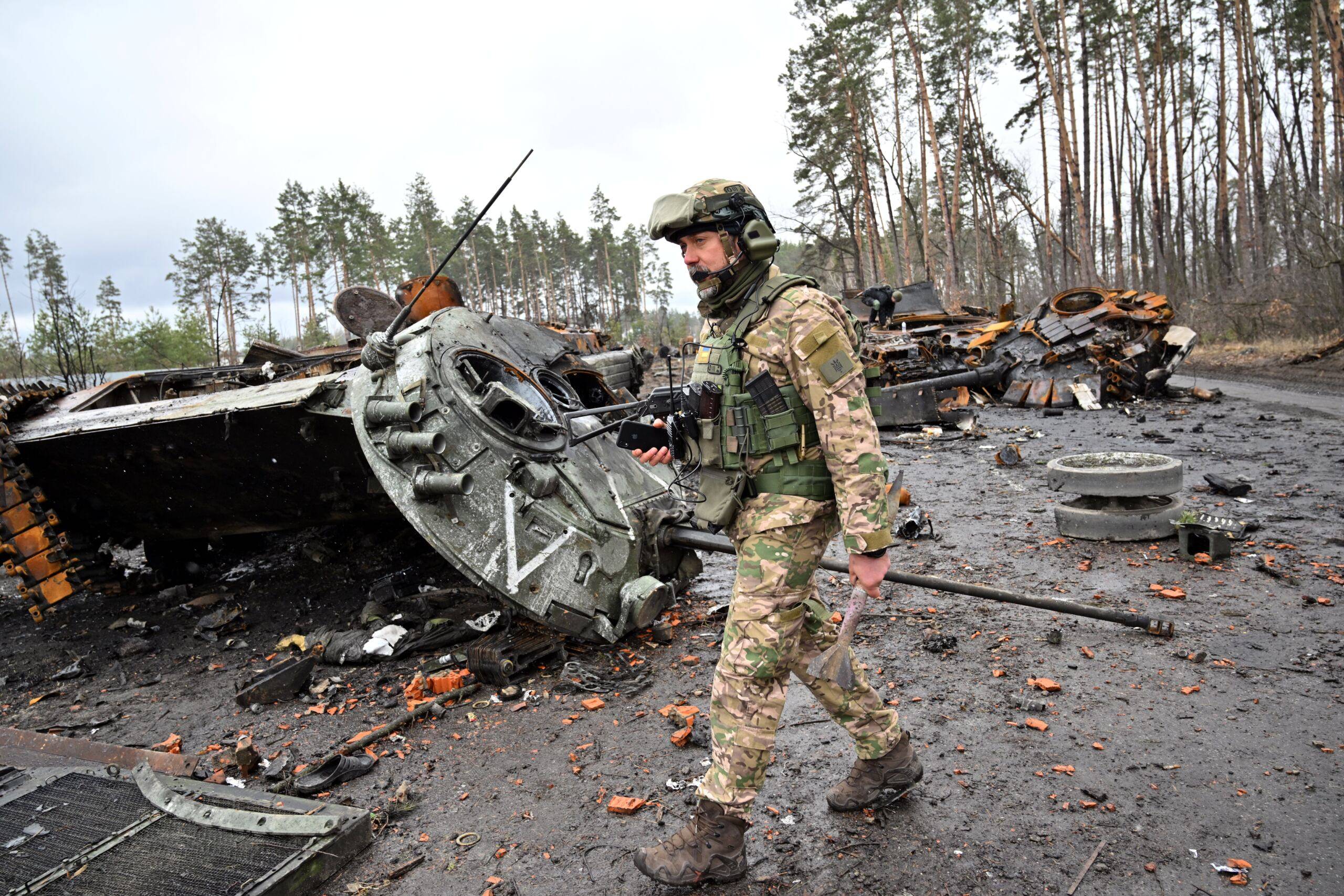 Żołnierz idzie obok zniszczonego czołgu