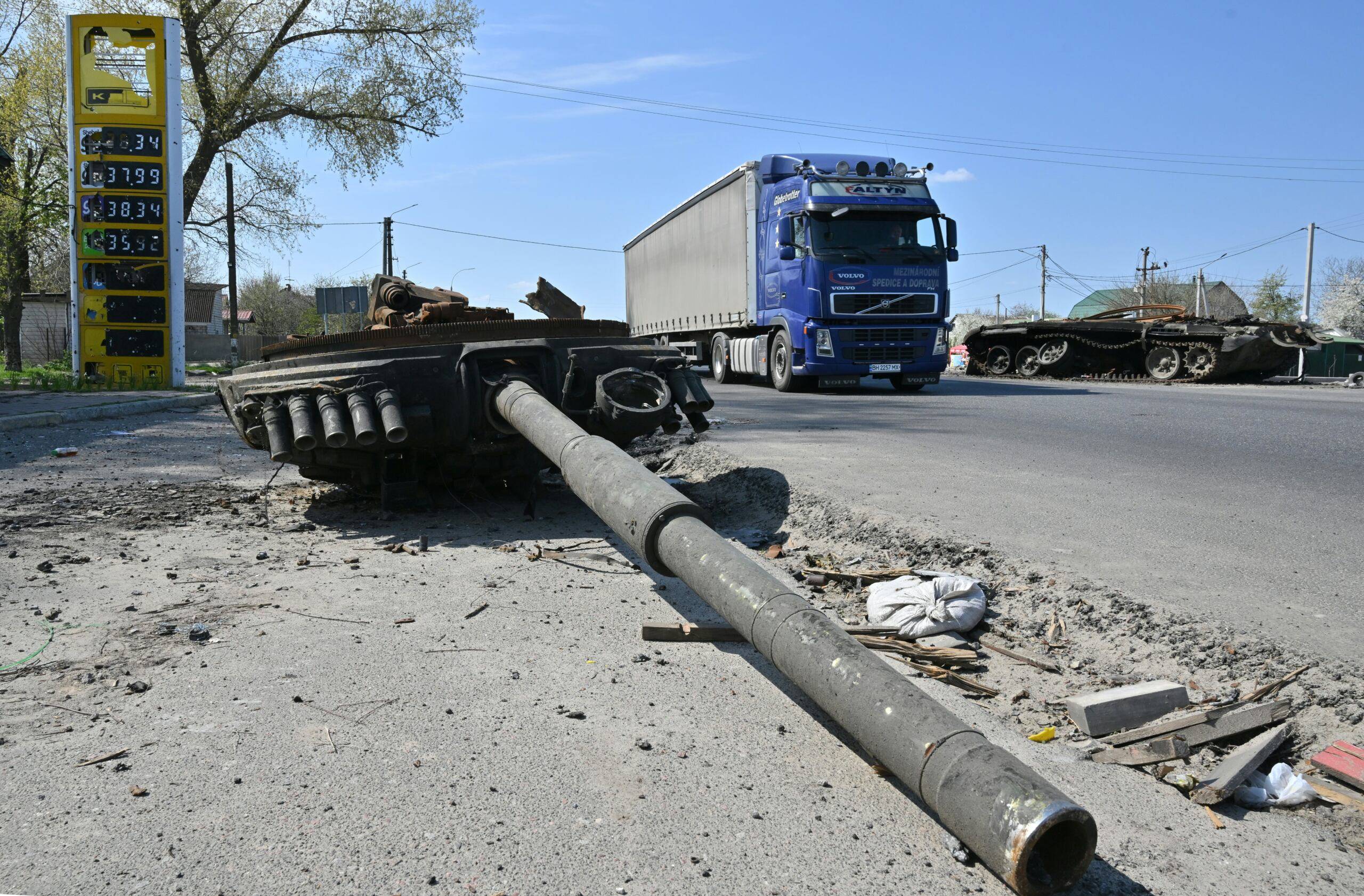 A truck drive past a wreckage of a Russian tank next to a destroyed petrol station in Skybyn village, northeastern Ukrainian capital of Kyiv on May 2, 2022. - The snaking queues of cars that returned to many Ukrainian roads last week showcase the success of Russia's seeming effort to inflict as much pain on its western neighbour as possible. (Photo by Sergei SUPINSKY / AFP)
