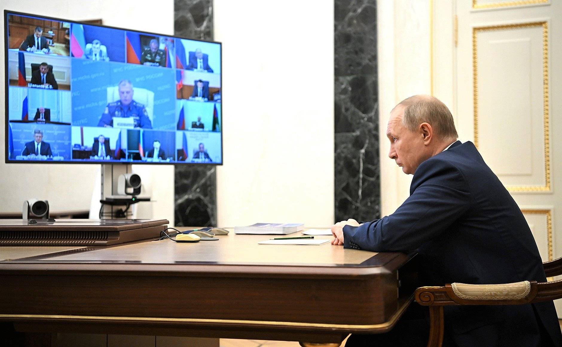 Putin siedzi, ma zaciśnięte wargi, na przeciw wielkiego monitora, na którym wyświetlają się uczestnicy spotkania online