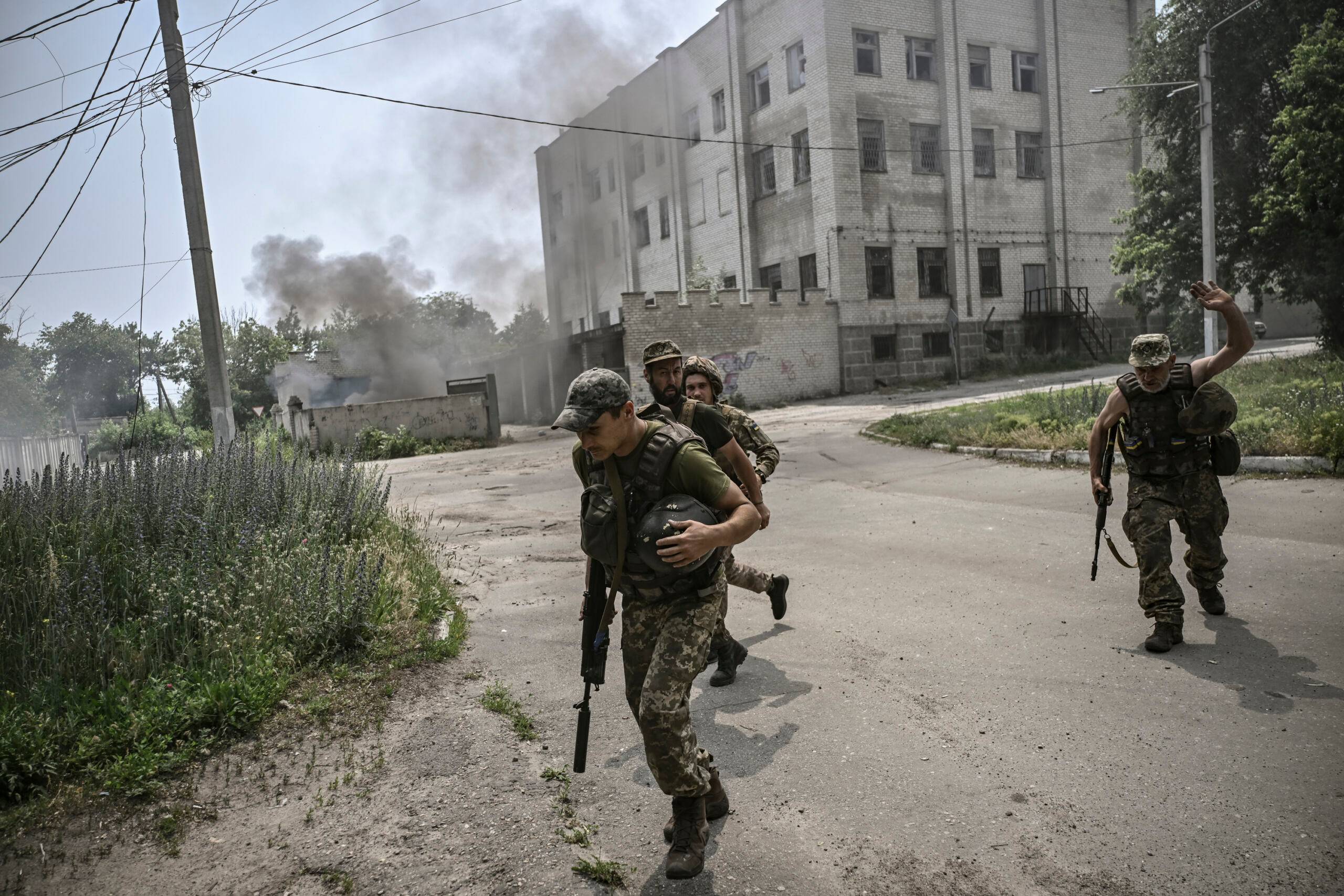 Ukrainian servicemen run for cover during an artillery duel between Ukrainian and Russian troops in the city of Lysychansk, eastern Ukrainian region of Donbas, on June 11, 2022. (Photo by ARIS MESSINIS / AFP)