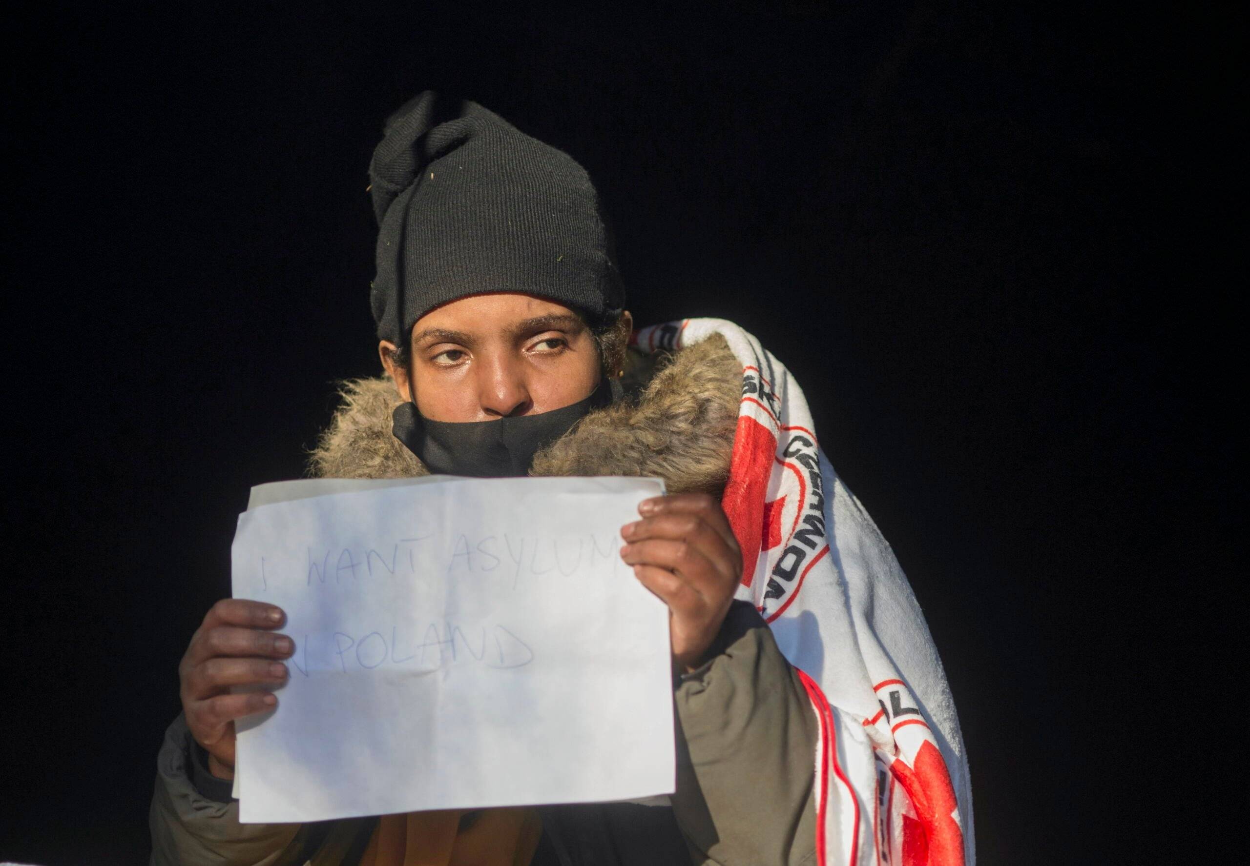 Okutana osoba z kartką z napisem po angielsku „Chcę azylu w Polsce"
