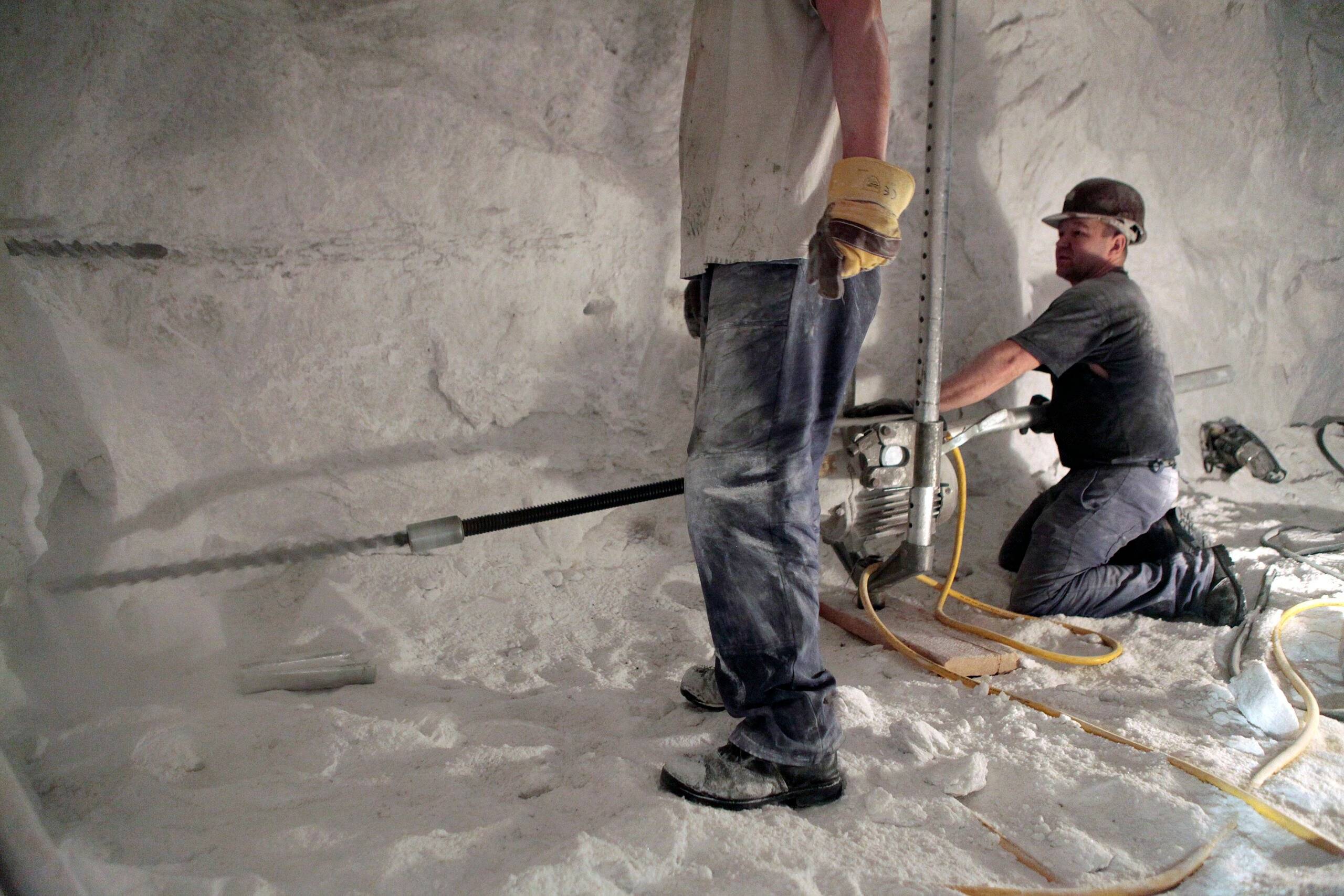 Klęczący mężczyzna pracuje przy ścianie w kopalni