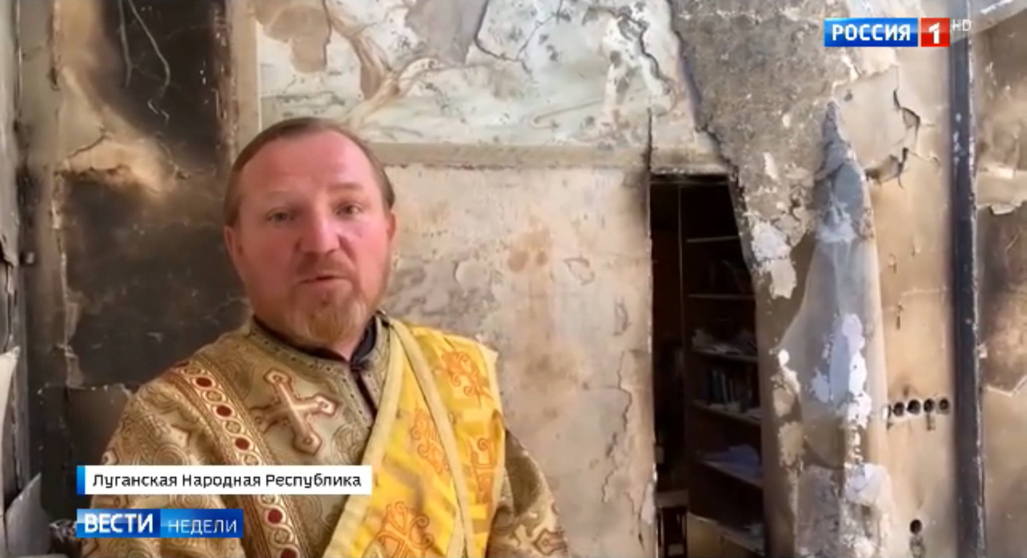 Mężczyzna w liturgicznych szatach na tle rozwalonej ściany