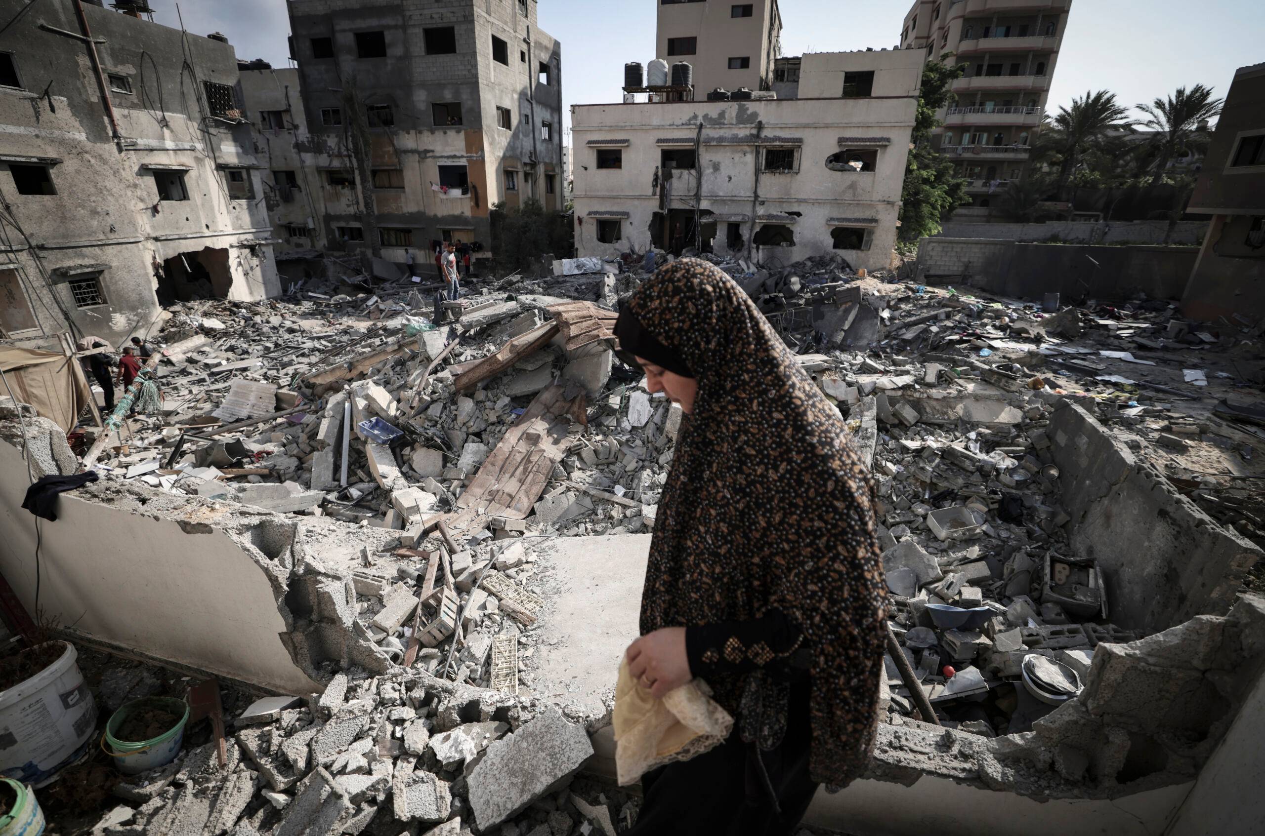 A Palestinian woman checks the damage as she walks through rubble in front of her home in Gaza city early on August 8, 2022, following a cease fire between Israel and Palestinian militants. - Israel agreed last night to an Egyptian proposed truce with in Gaza with Islamic Jihad after three days of intense conflict. (Photo by Mahmud HAMS / AFP)