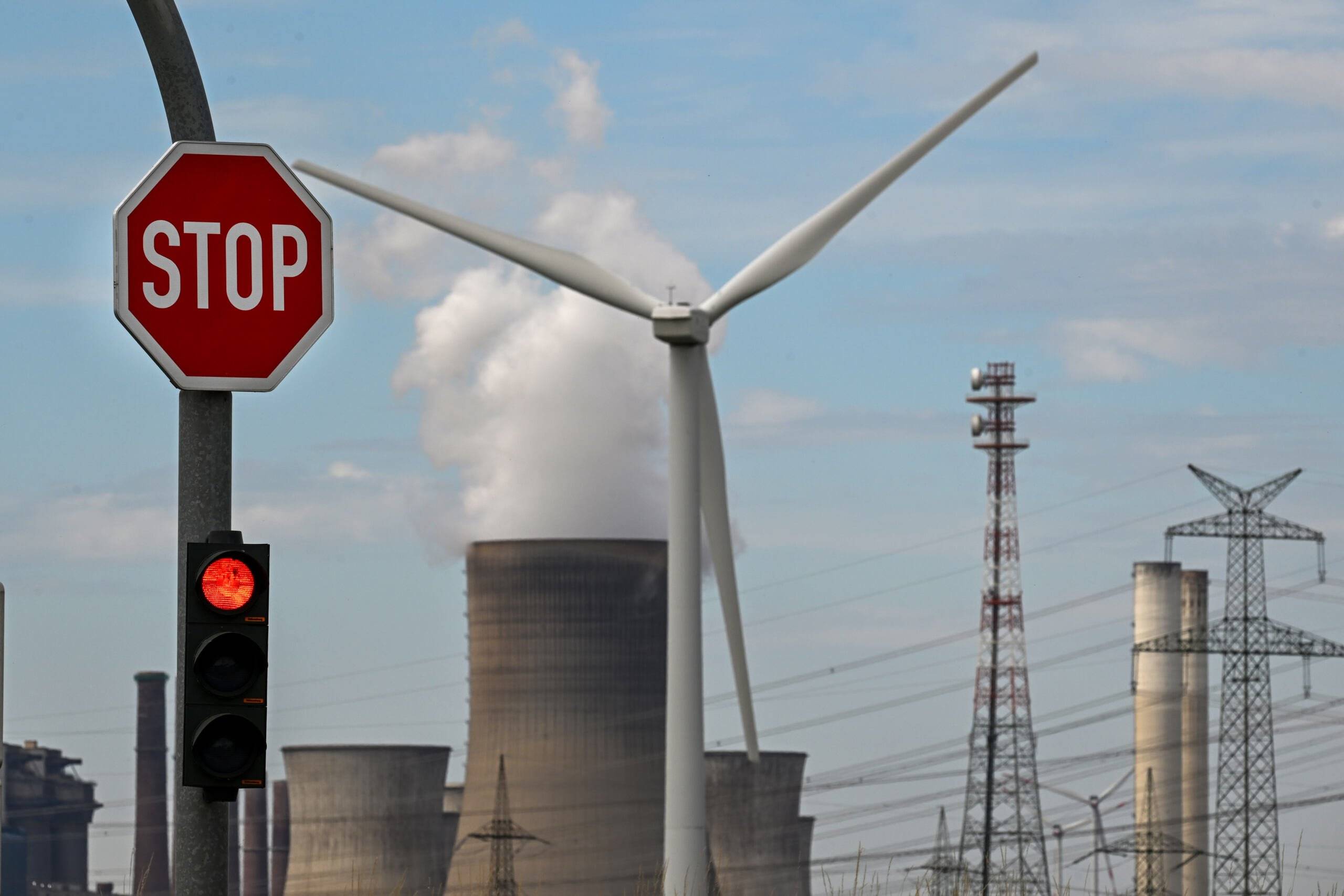 A stop sign and a wind turbine are seen in front of a coal-fired power plant operated by German energy supplier RWE in Niederaussem, western Germany, on July 13, 2022. - In response to a squeeze of Russian gas supplies, Germany has reactivated mothballed coal power plants to take the burden off gas. (Photo by Ina FASSBENDER / AFP)