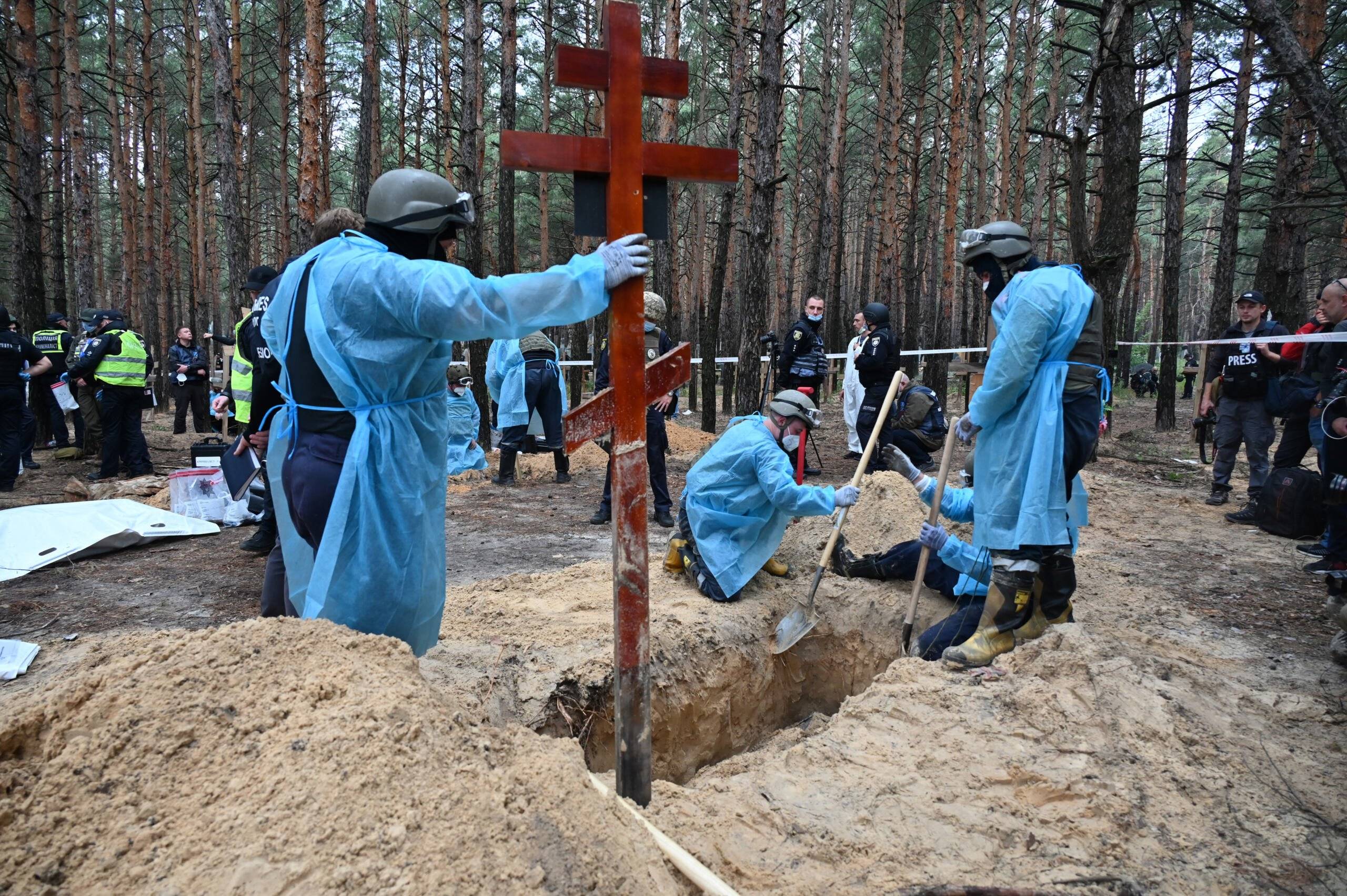 Forensic technicians dig a grave in a forest on the outskirts of Izyum, eastern Ukraine on September 16, 2022. - Ukraine said on September 16, 2022 it had counted 450 graves at just one burial site near Izyum after recapturing the eastern city from the Russians. (Photo by SERGEY BOBOK / AFP)