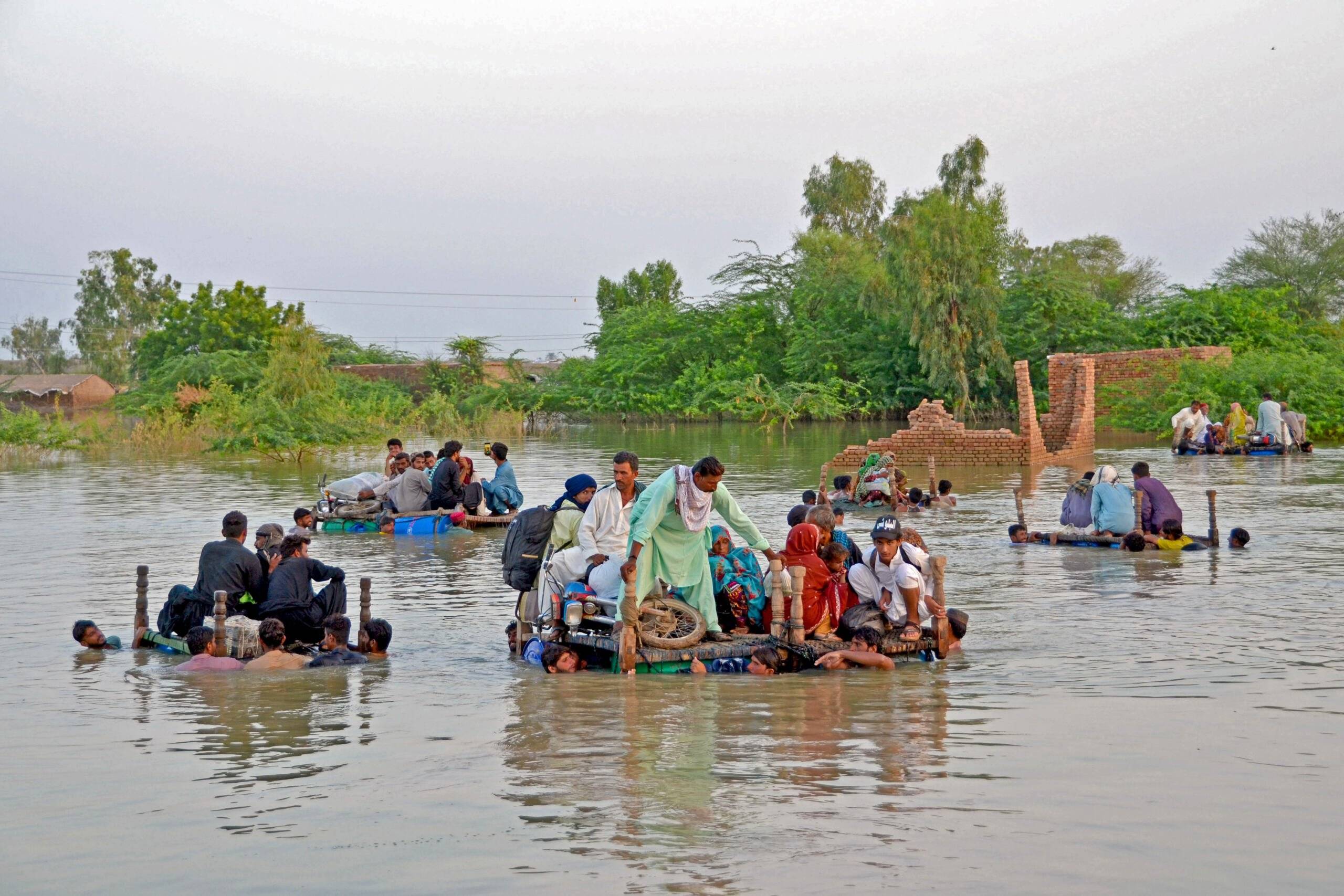 Internally displaced people wade through floodwaters after heavy monsoon rains in Jaffarabad district in Balochistan province on September 8, 2022. - Record monsoon rains have caused devastating floods across Pakistan since June, killing more than 1,200 people and leaving almost a third of the country under water, affecting the lives of 33 million. (Photo by Fida HUSSAIN / AFP)