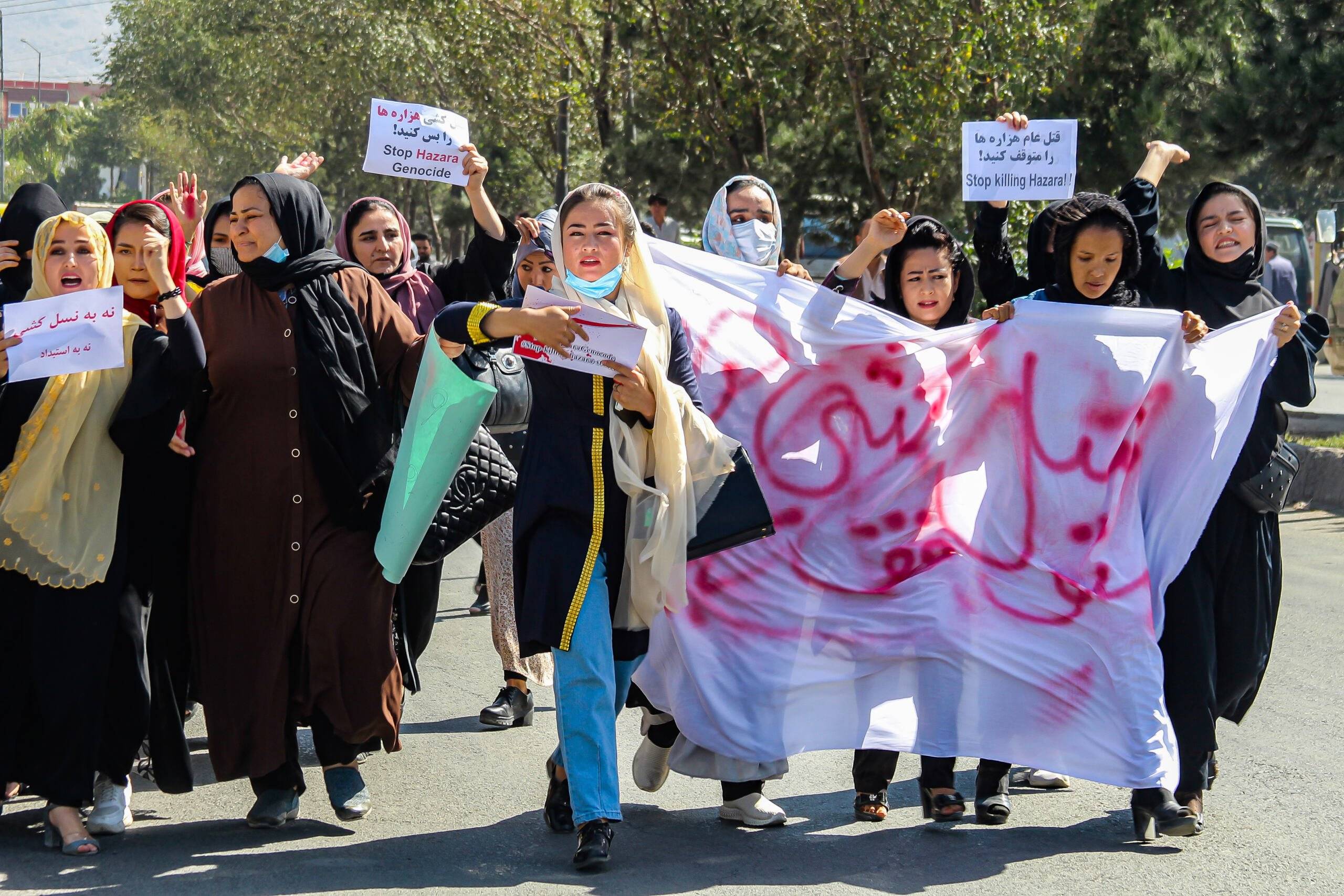 Afghan women display placards and chant slogans during a protest they call Stop Hazara genocide a day after a suicide bomb attack at Dasht-e-Barchi learning centre, in Kabul on October 1, 2022. - Dozens of women from Afghanistan's minority Hazara community protested in the capital October 1, after a suicide bombing a day earlier killed 20 people. (Photo by - / AFP)