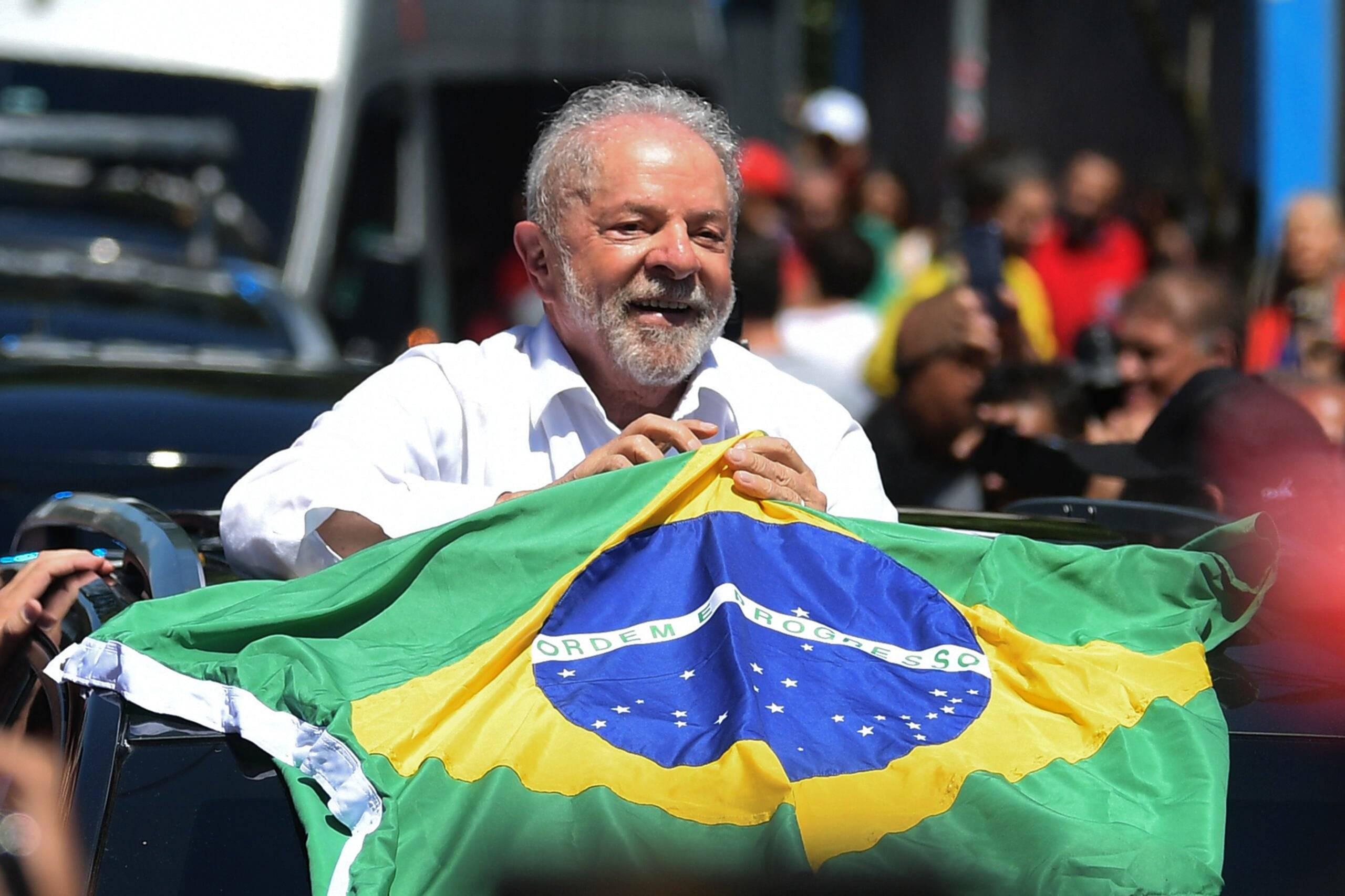Brazilian former President (2003-2010) and candidate for the leftist Workers Party (PT) Luiz Inacio Lula da Silva holds a Brazilian flag while leaving a polling station during the presidential run-off election, in Sao Paulo, Brazil, on October 30, 2022. - After a bitterly divisive campaign and inconclusive first-round vote, Brazil elects its next president in a cliffhanger runoff between far-right incumbent Jair Bolsonaro and veteran leftist Luiz Inacio Lula da Silva. (Photo by CARL DE SOUZA / AFP)
