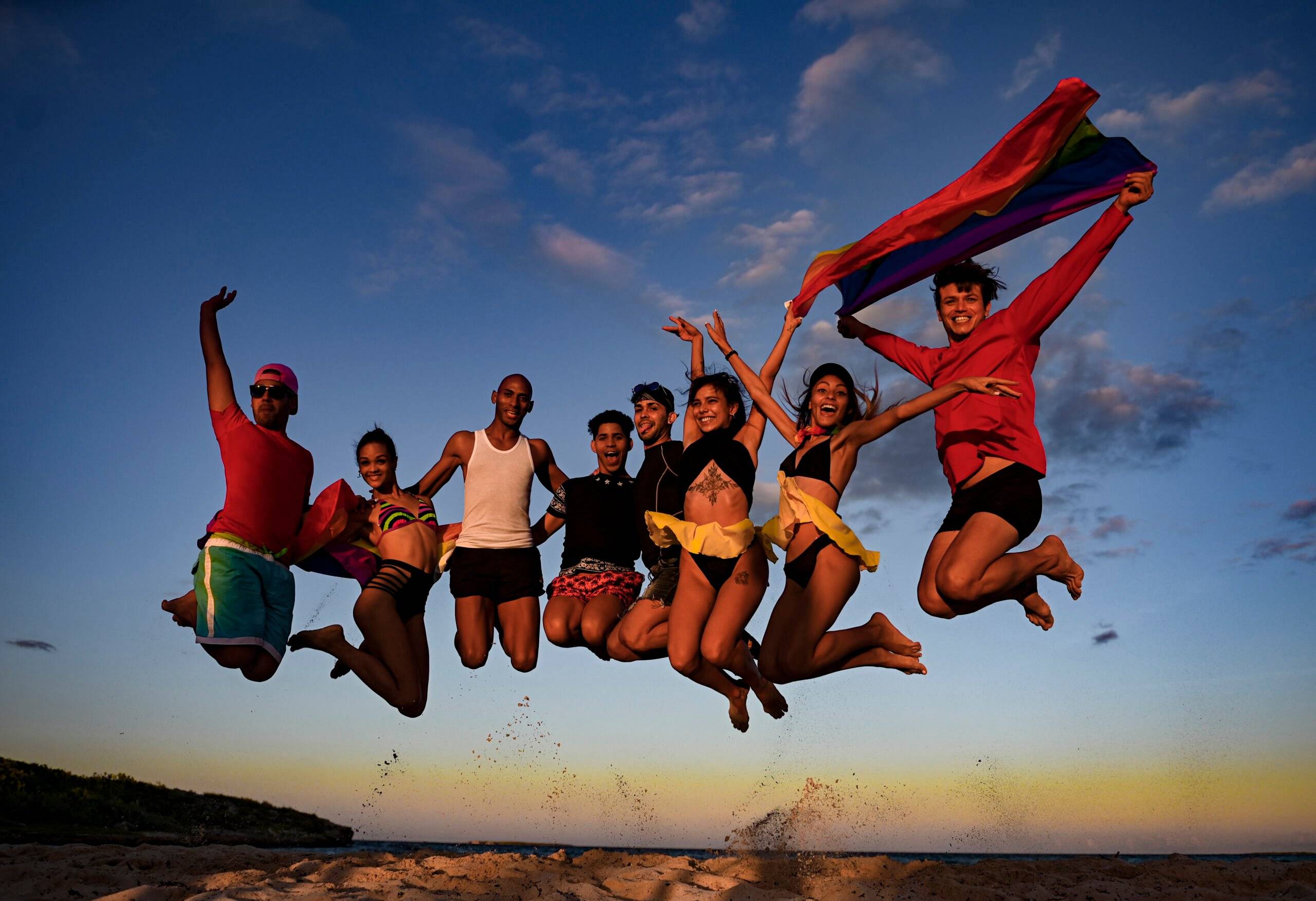 Cheerleading team jumps with LGBT flags at the Gran Muthu Rainbow Hotel, in Guillermo Key in Ciego de Avila Province, Cuba, on November 27, 2021. - Cuba's first LGBT hotel, which had been inaugurated in December 2019, but very soon had to close due to the coronavirus pandemic, reopened to attract that tourist segment at a time when authorities are studying the approval of equal marriage on the island. Under all preventive sanitary measures, this five-star accommodation received its first clients again on November 15, when Cuba reopened its borders after 10 months of confinement. (Photo by YAMIL LAGE / AFP)