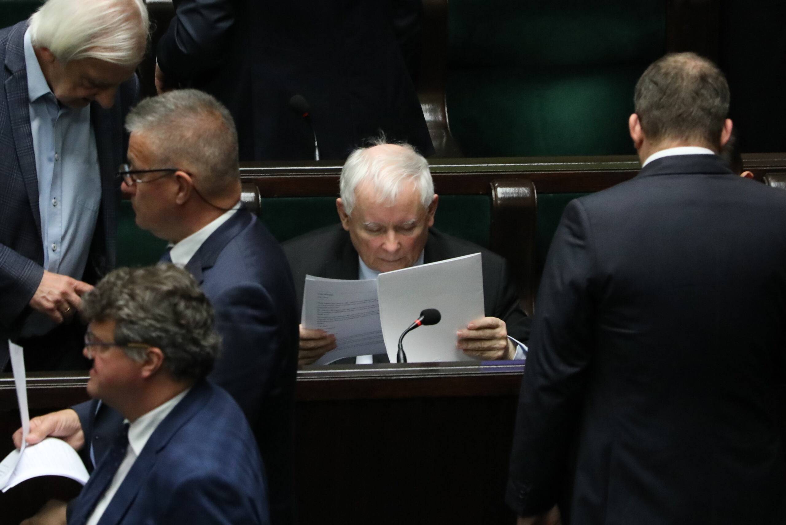 Jarosław Kaczyński czyta dokumenty, siedząc w ławach sejmowycj