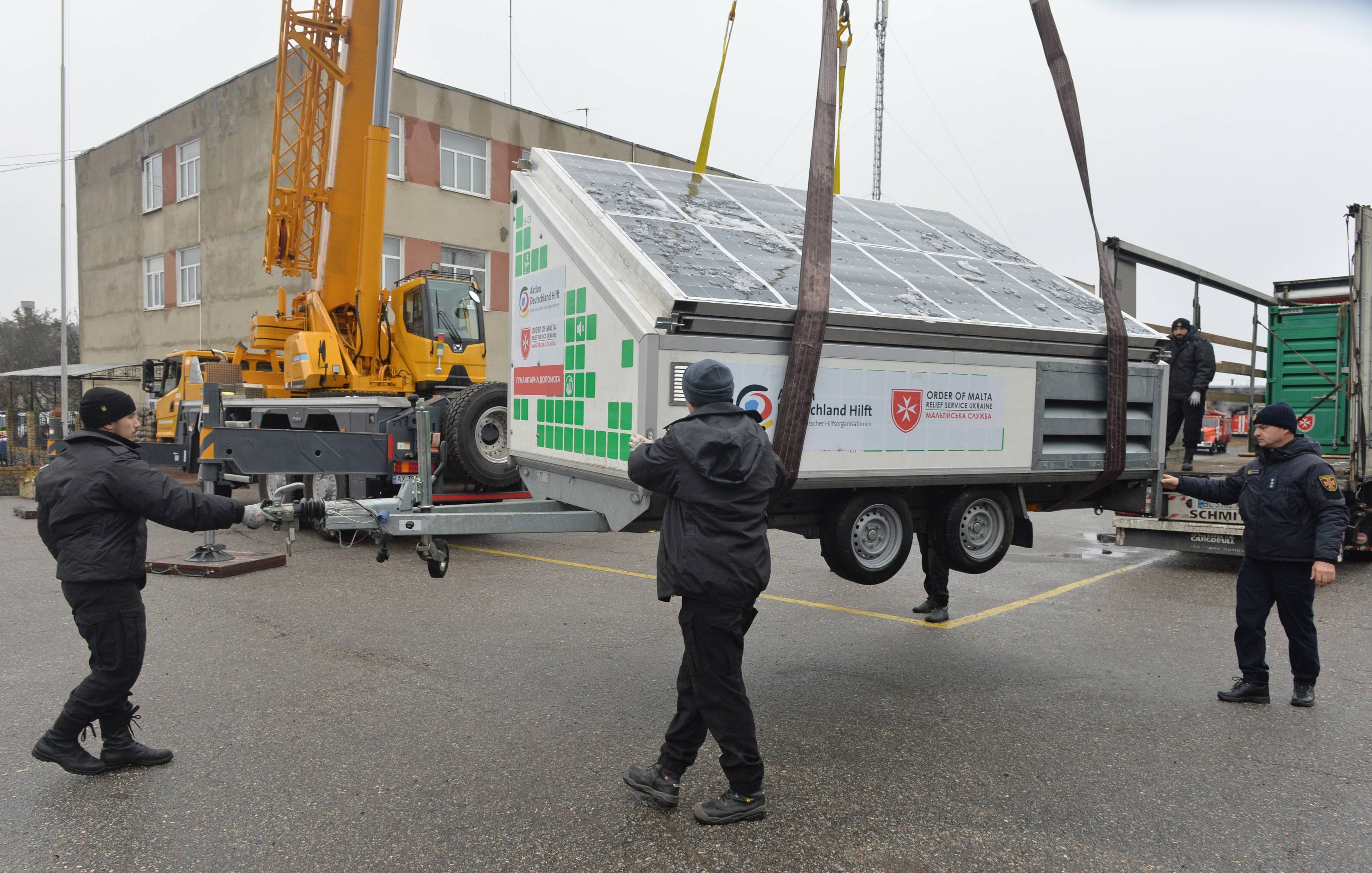 Employees of the State Emergency Service of Ukraine unload mobile power generating station as part of international humanitarian aid in the city of Kharkiv on November 21, 2022, amid the Russian military invasion of Ukraine. - The station will be used to provide electricity to rescuers and the local population in areas where there is no power supply due to the destruction of energy infrastructure facilities by the Russian army. (Photo by SERGEY BOBOK / AFP)