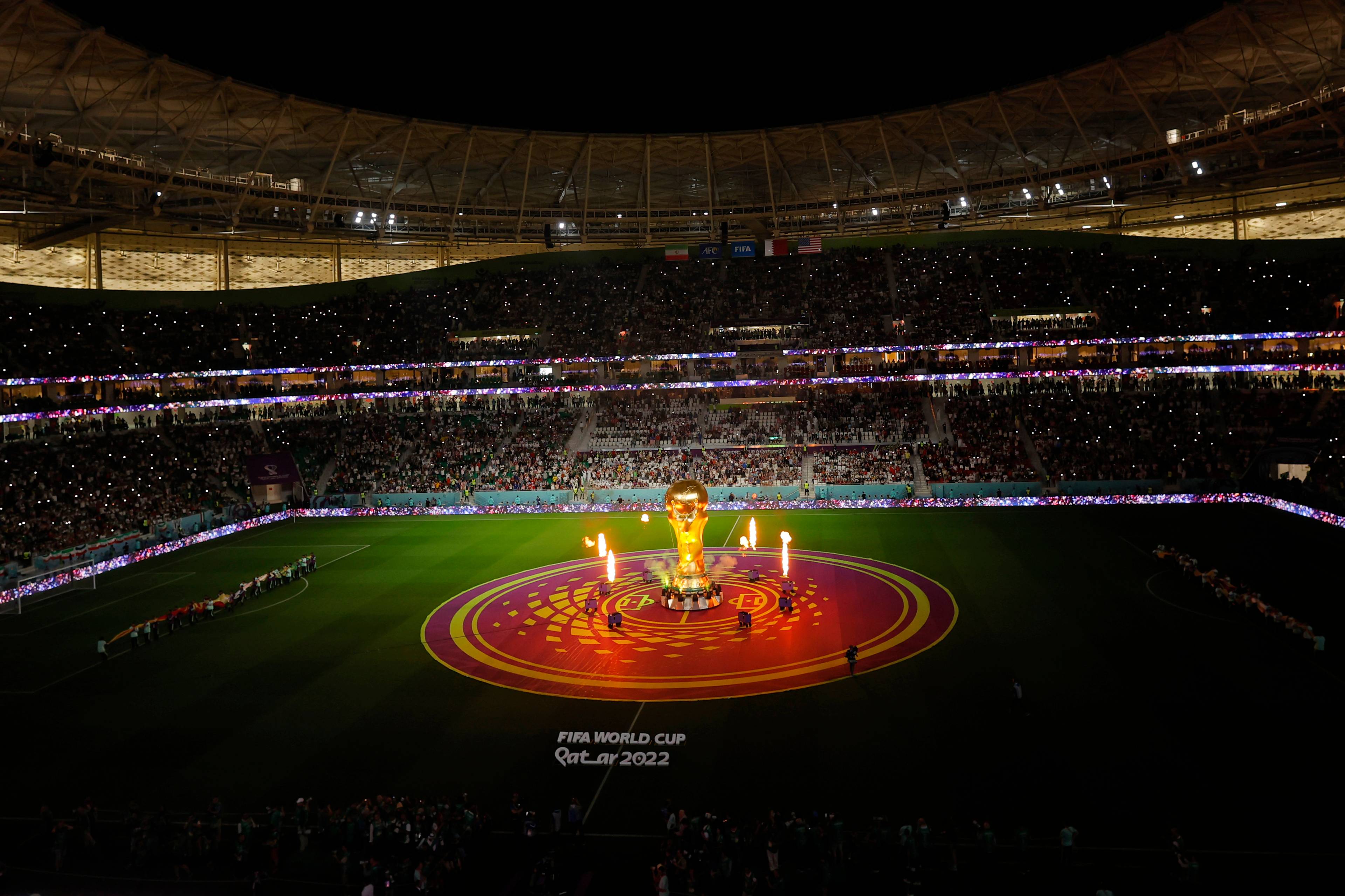 Fireworks go off around a replica of the World Cup trophy during the Qatar 2022 World Cup Group B football match between Iran and USA at the Al-Thumama Stadium in Doha on November 29, 2022. (Photo by Odd ANDERSEN / AFP)