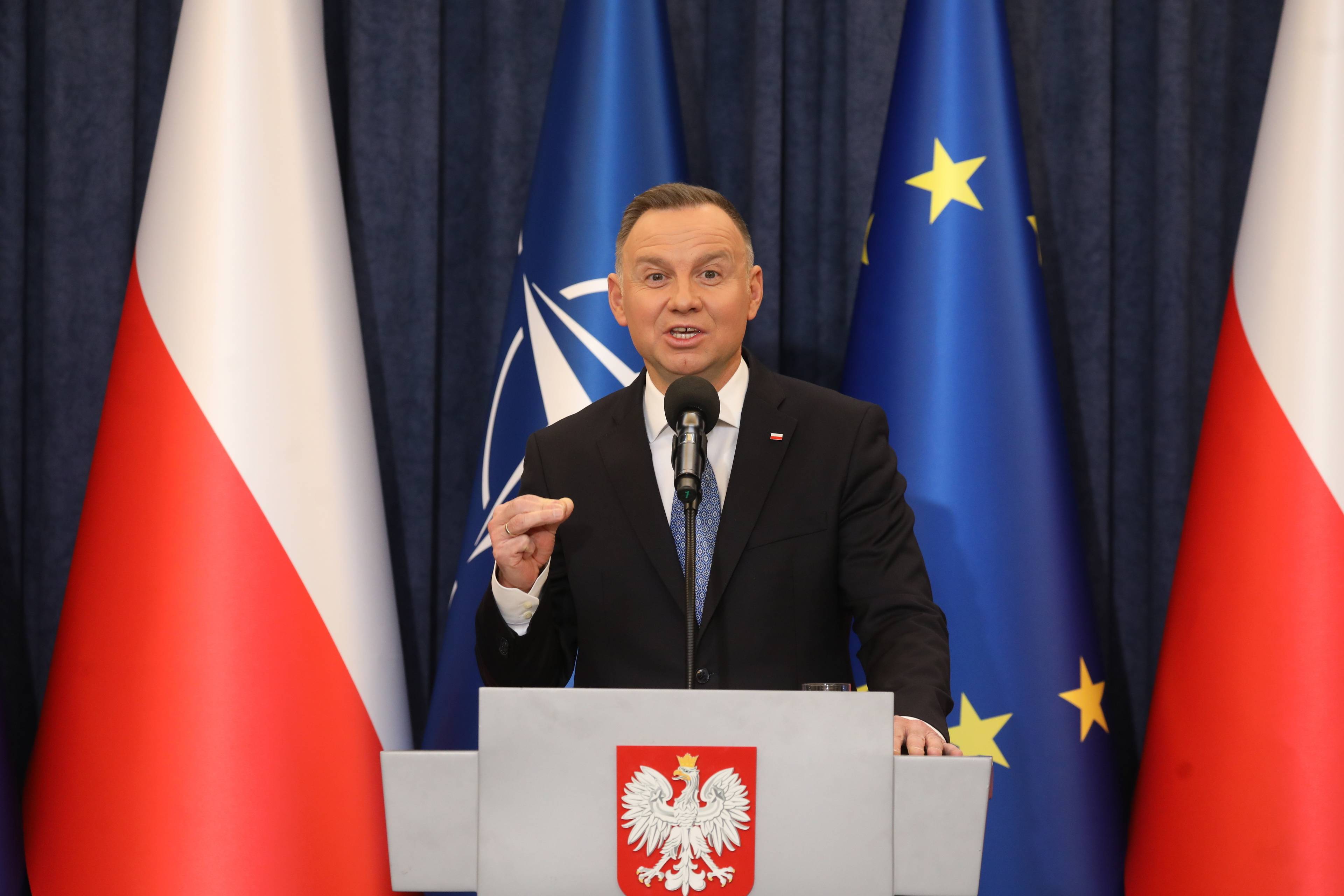 Prezydent Andrzej Duda przemawia za mównicą z godłem Polski