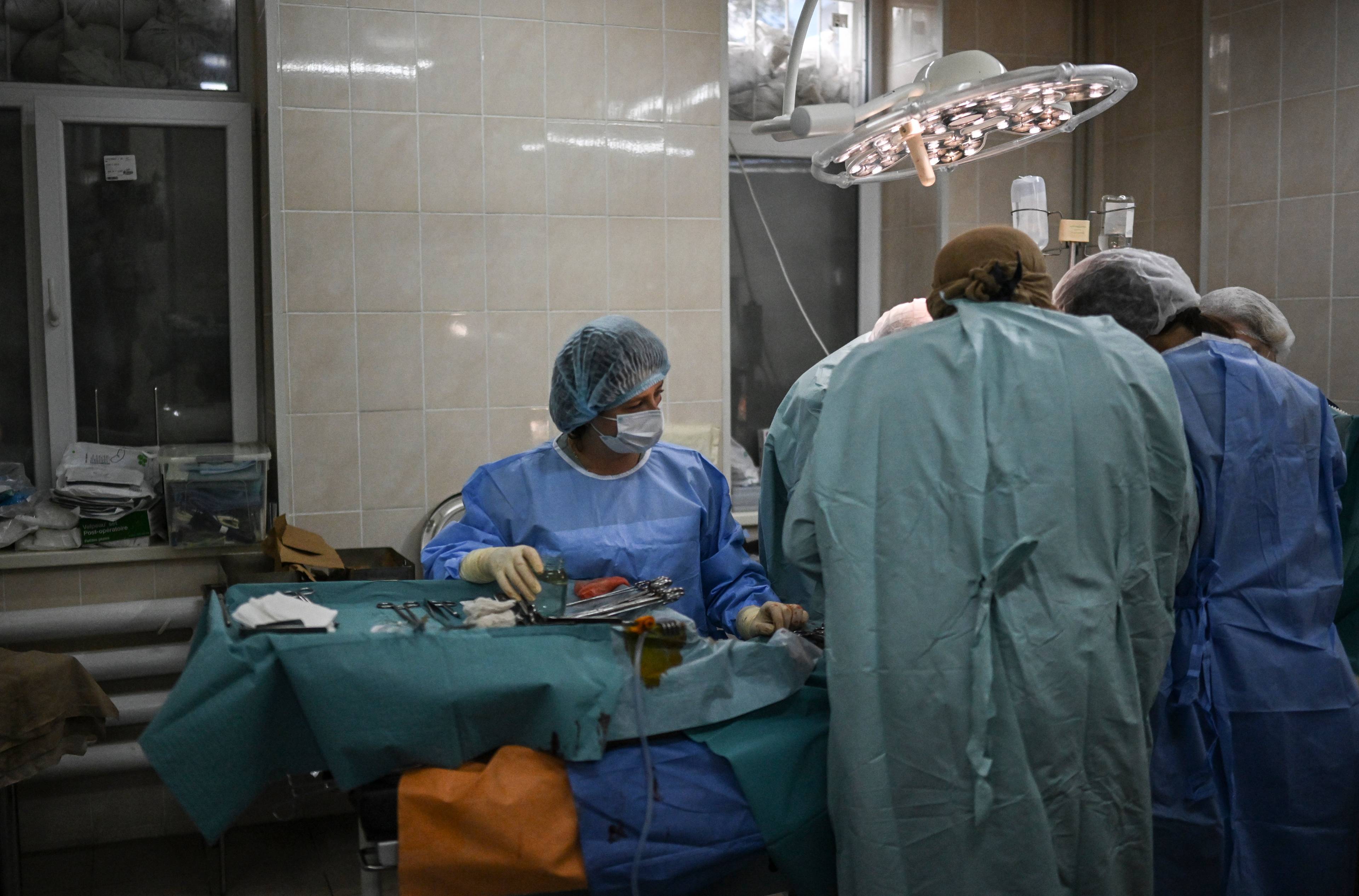 Sala operacyjna. Lekarze w zielonych kitlach operują pacjenta