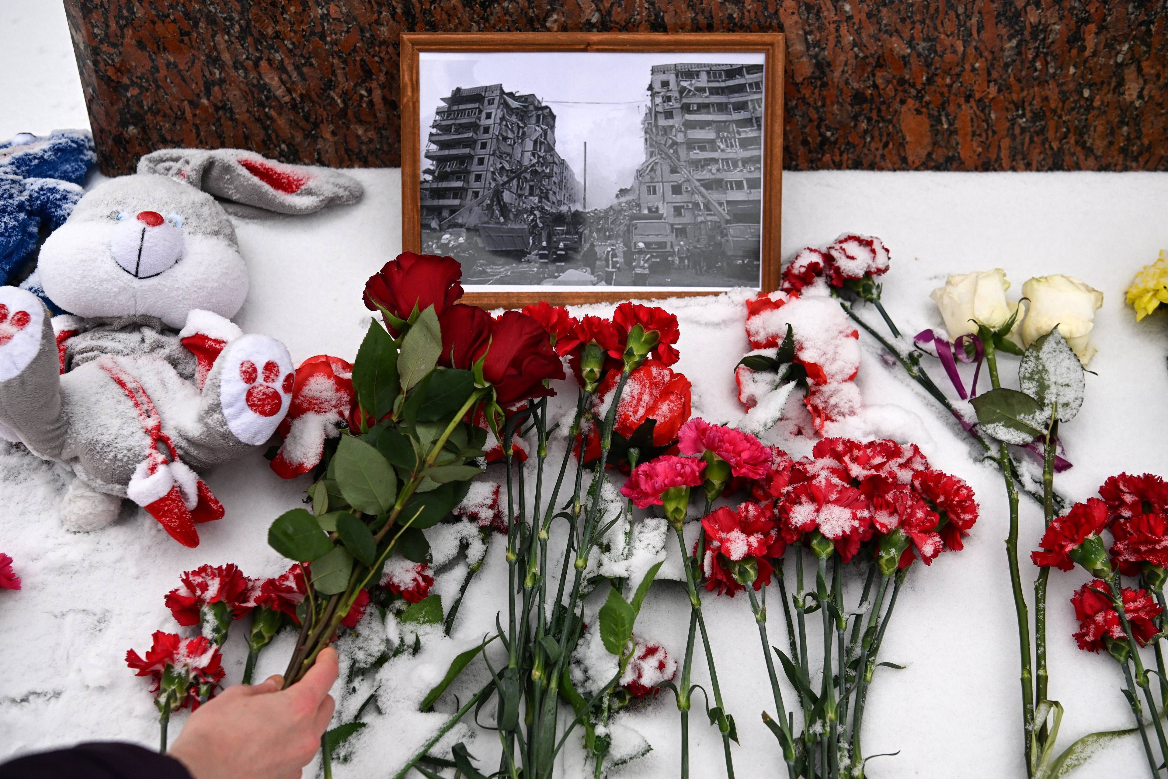 A person lays flowers in memory of those killed in the weekend strike on a residential block in the Ukrainian city of Dnipro, at the monument to famous Ukrainian poetess Lesya Ukrainka in Moscow on January 17, 2023. (Photo by - / AFP)