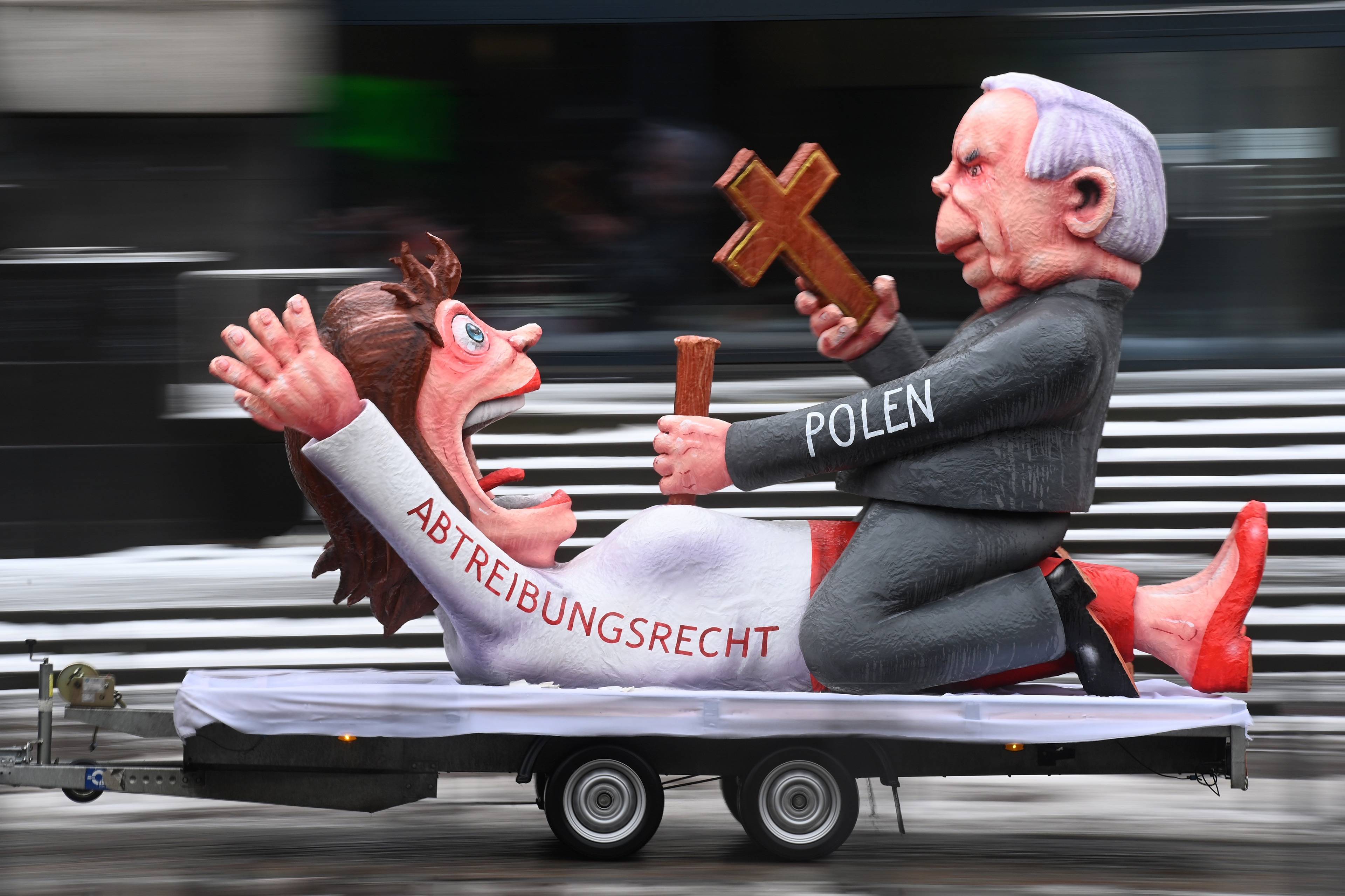 kukła przedstawiająca Jarosława Kaczyńskiego, który siedzi okrakiem na kobiecie i wbija jej w brzuch kołek drewniany za pomocą krzyża, kobieta ma na sukience napis w języku niemieckim prawo do aborcji. Instalacja na platformie samochodowej