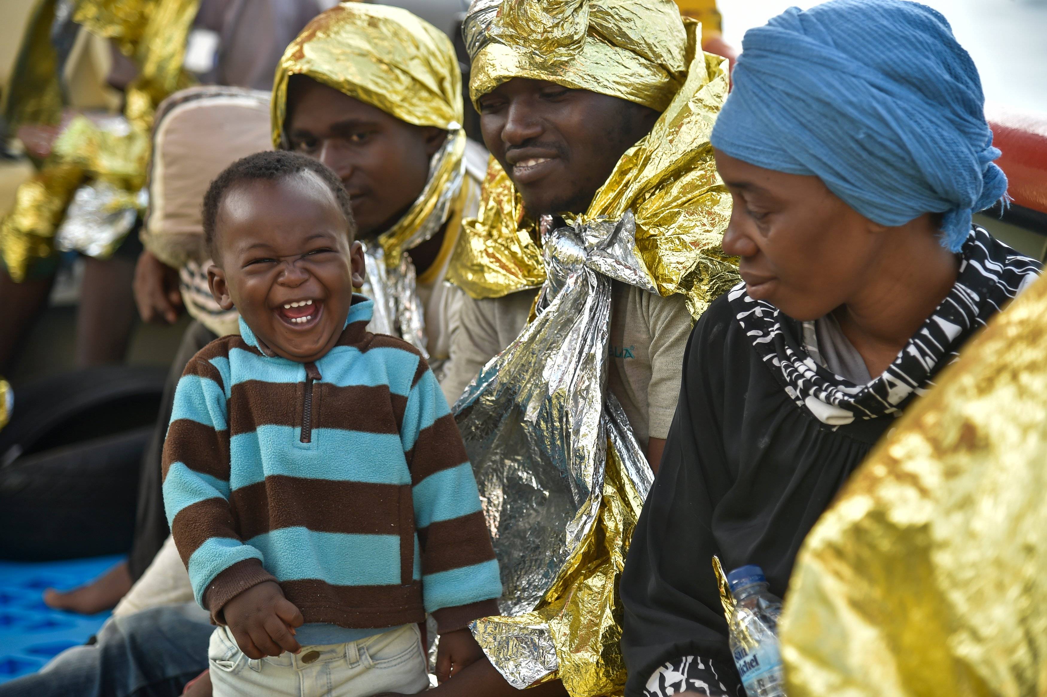 kobiety z Afryki owinięte w koce termiczne, na pierwszym planie śmiejący się chłopczyk