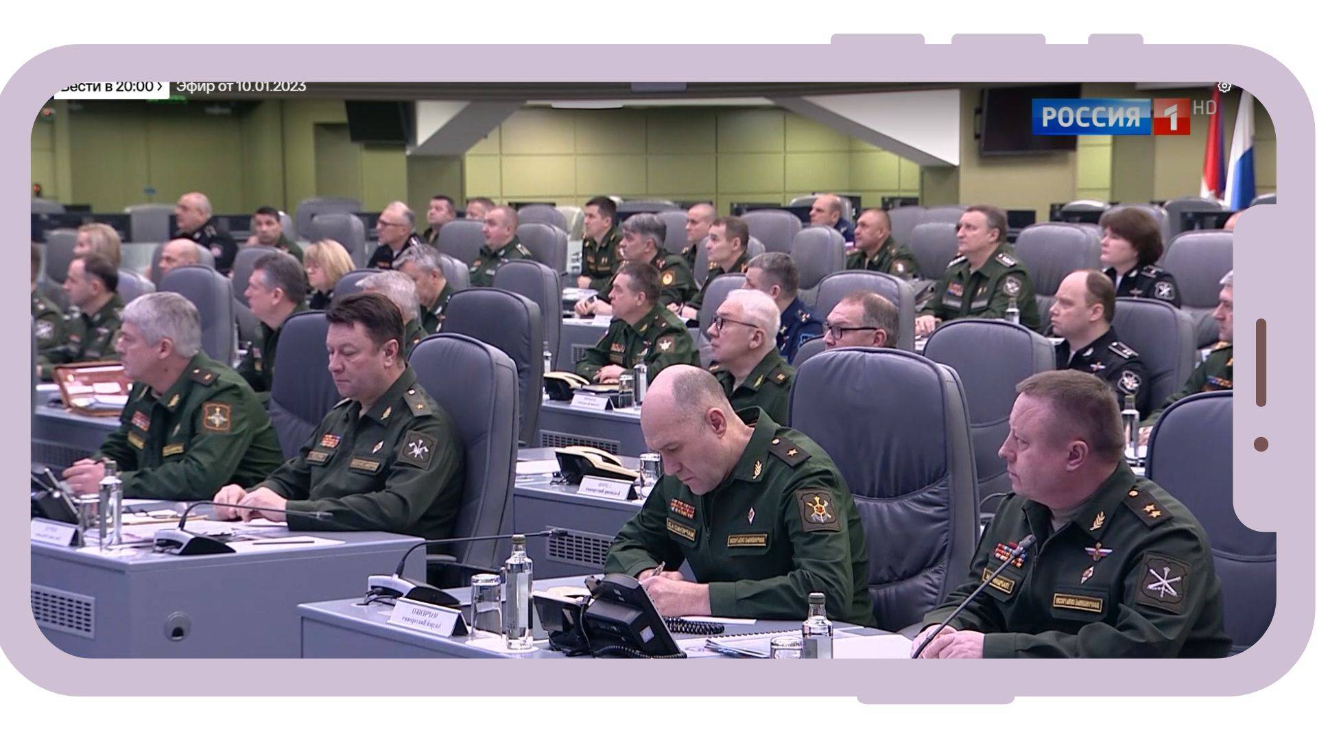 Grafika: w ramce telefonu komurkowego zdjęcie rosyjskich wojskowych notujących w sali konferencyjnej