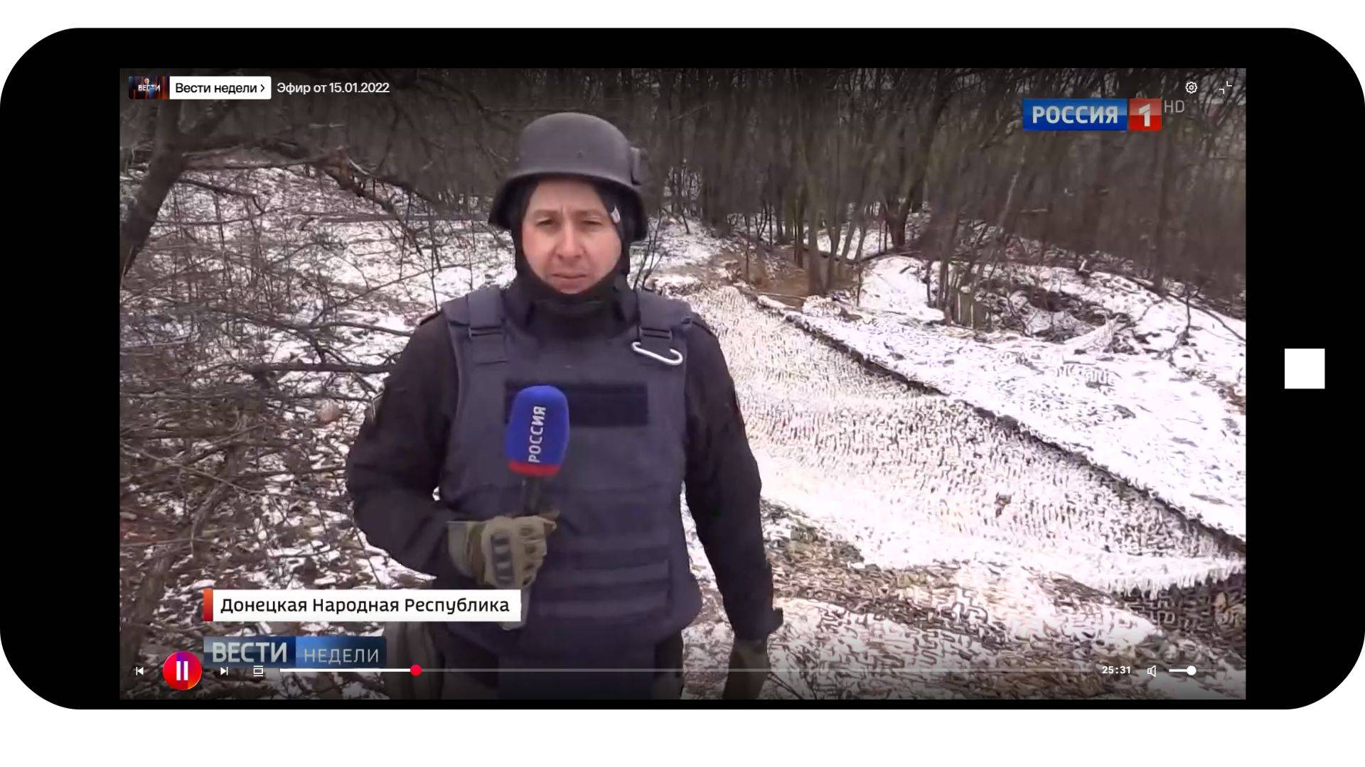 Grafika: w ramkę telefonu komórkowego wklejone zdjęcie dziennikarza w hełmie i z mikrofonem z napisem Rossija 1