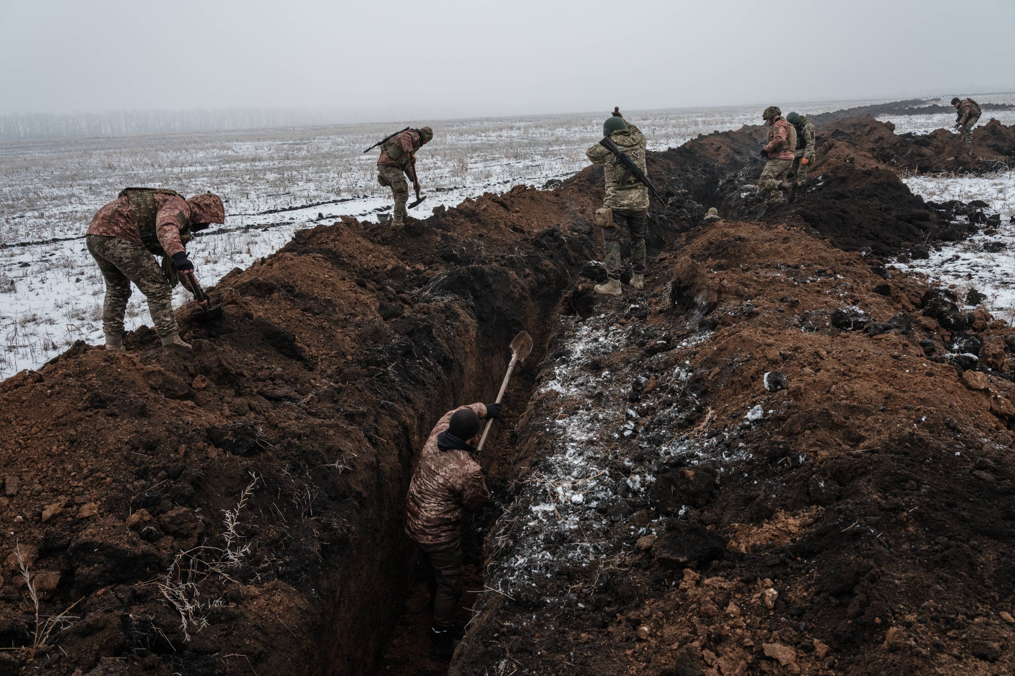 żołnierze kopią okopy w zaśnieżonym polu