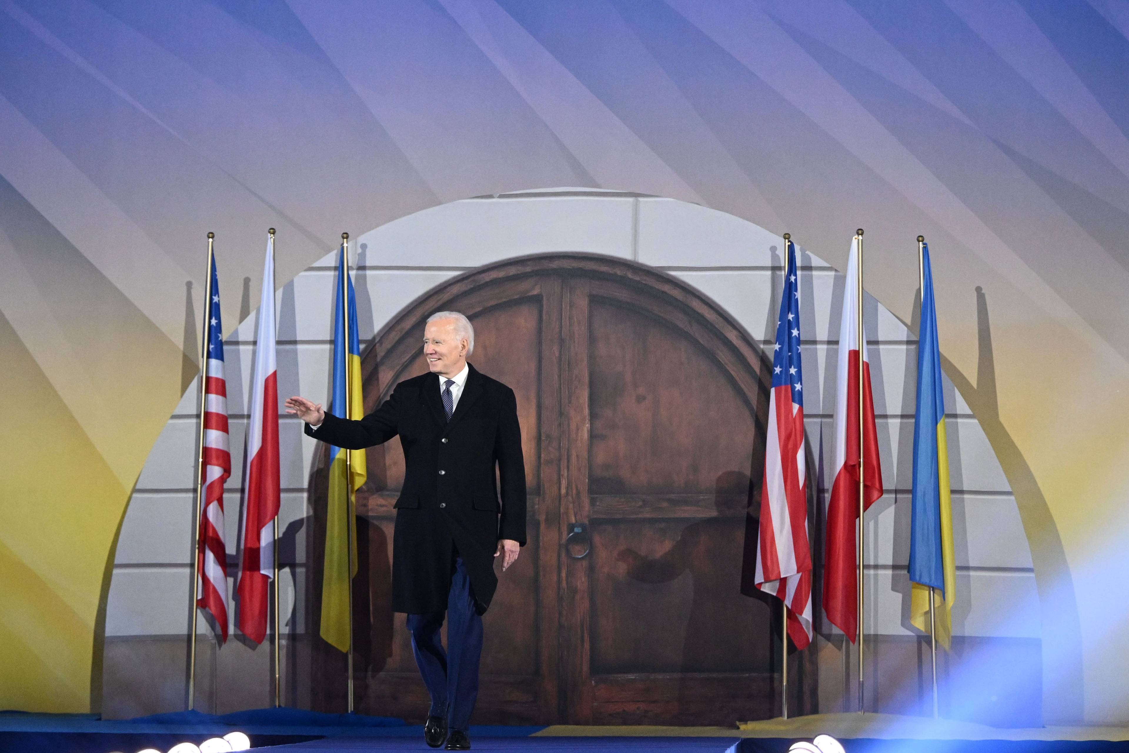 Joe Biden wychodzi na scenę przed przemówieniem w Warszawie, bo obu jego stronach trzy flagi: Polski, Ukrainy i Stanów Zjednoczonych