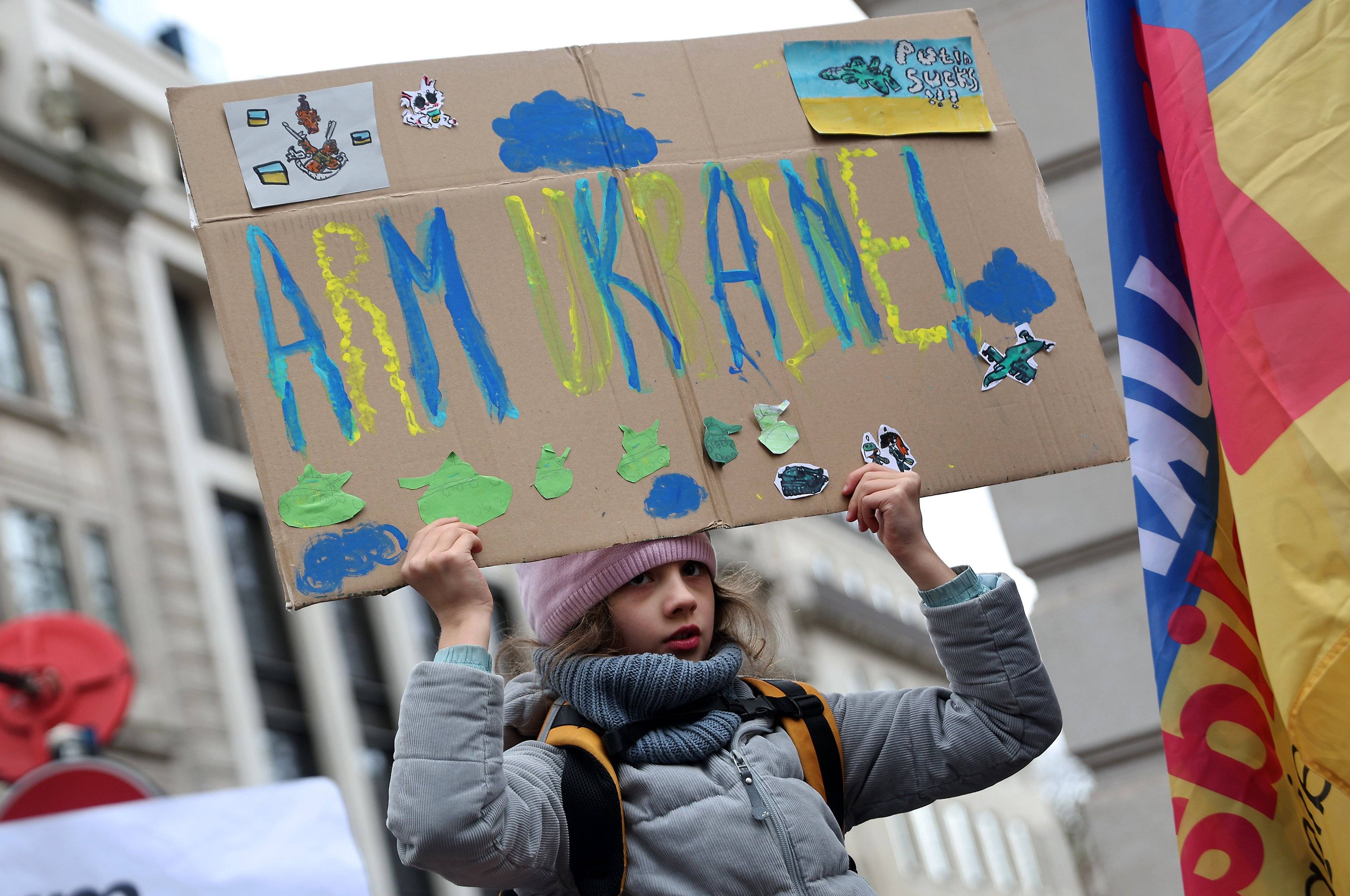 Dziewczynka trzyma nad głową napis „Arm Ukraine"
