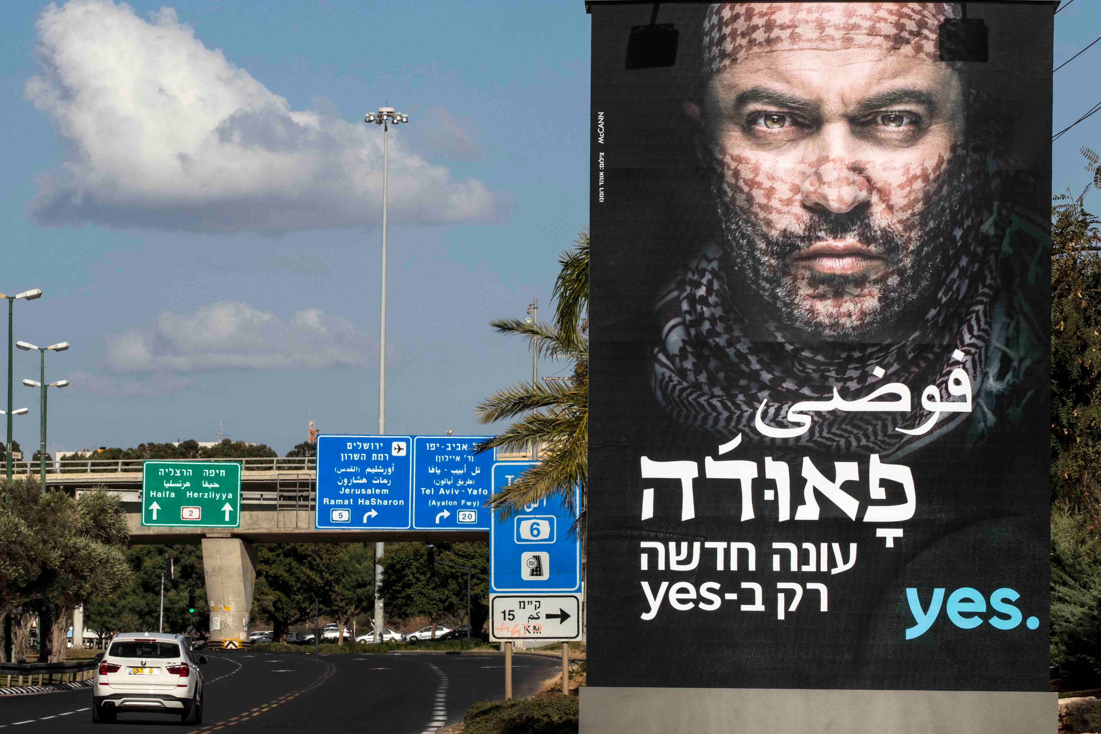bilboard z podobizną aktora Liora Raza i zapowiedzią nowego sezonu serialu Fauda w języku hebrajskim i arabskim