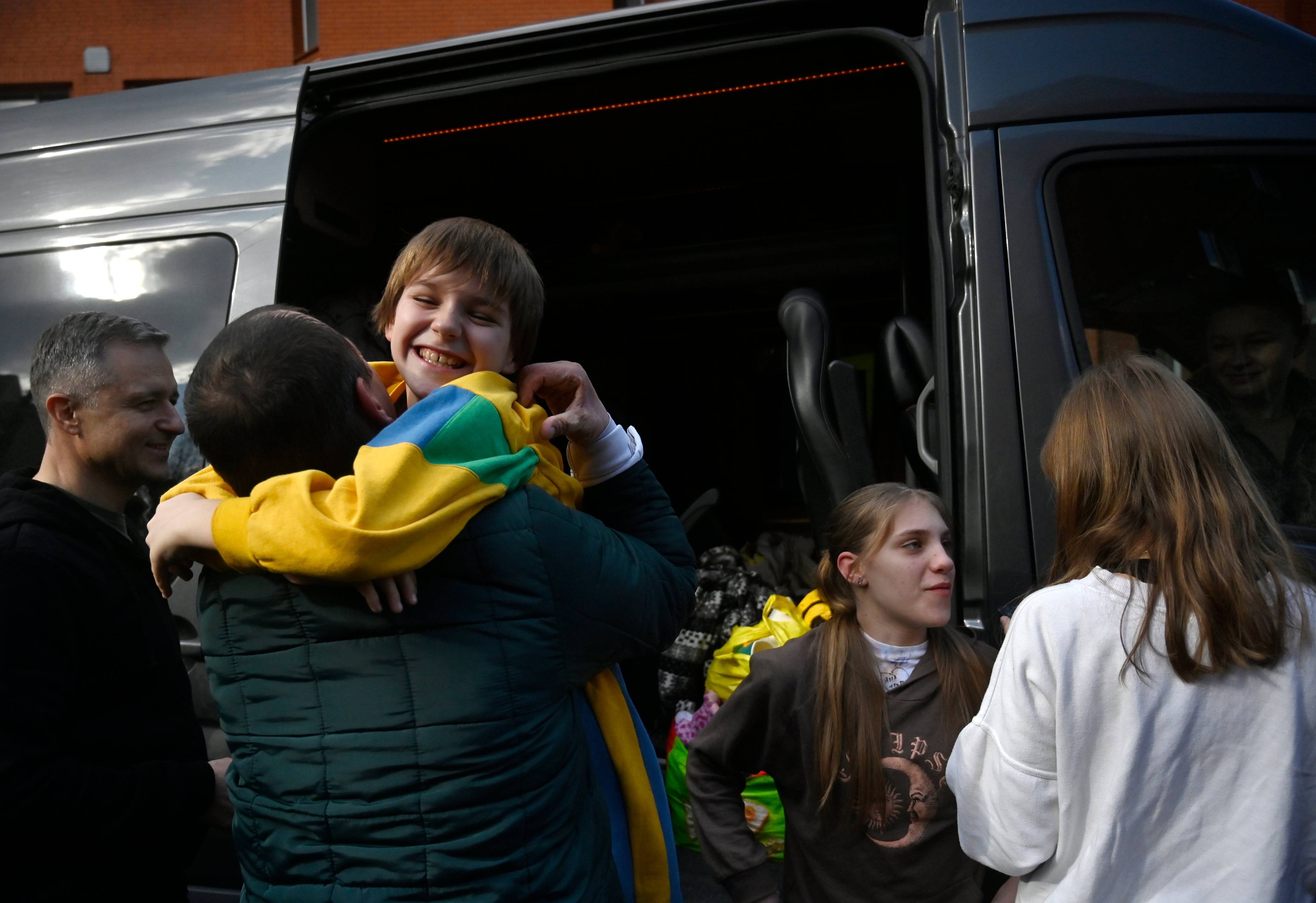 Chłopiec z ukraińską flagą smieje się w ramionach ojca