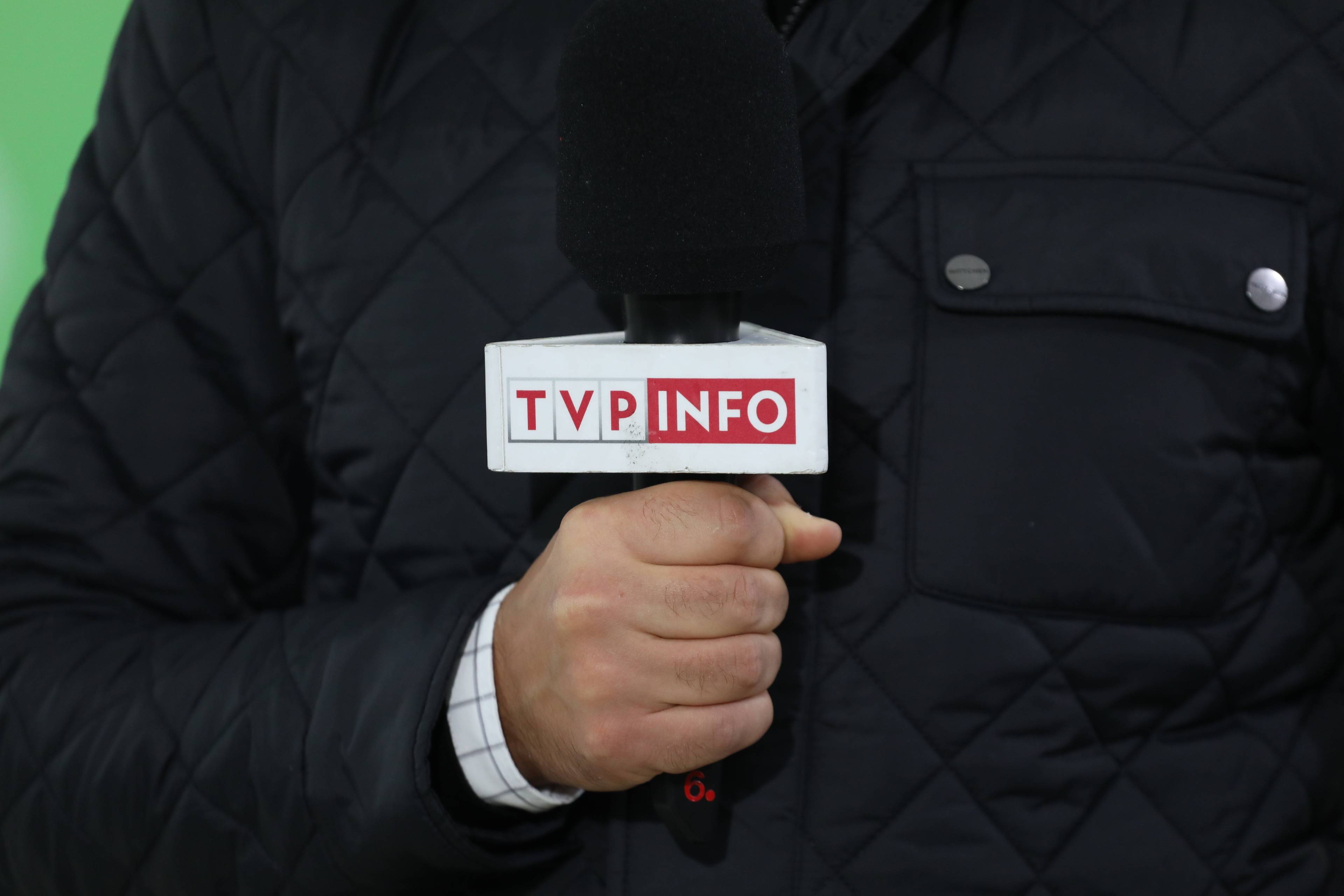 Mężczyzna trzyma mikrofon z napisem TVP Info