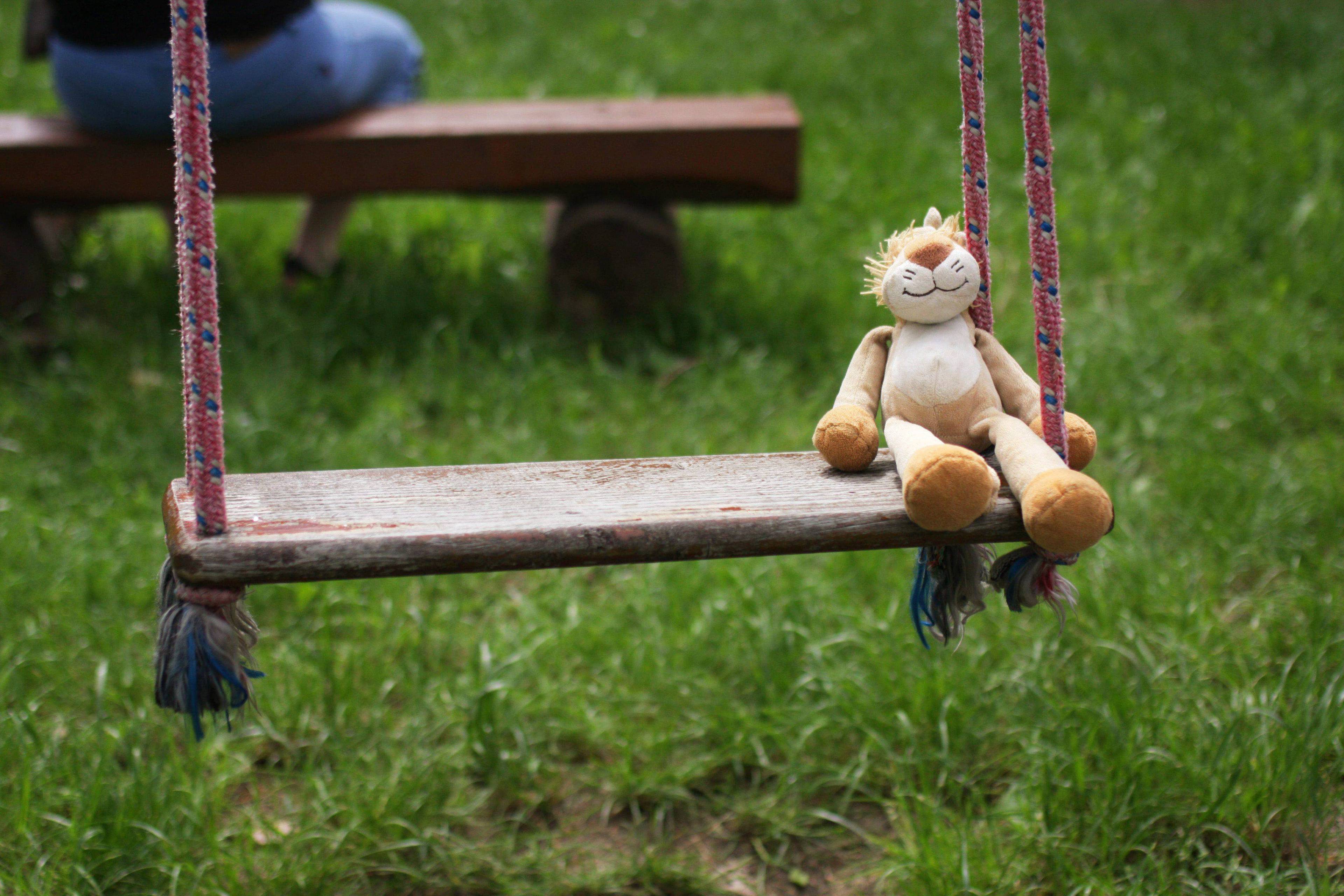 Na zdjęciu: plac zabaw dla dzieci, drweniana huśtawka a na niej pluszowa zabawka tygryska