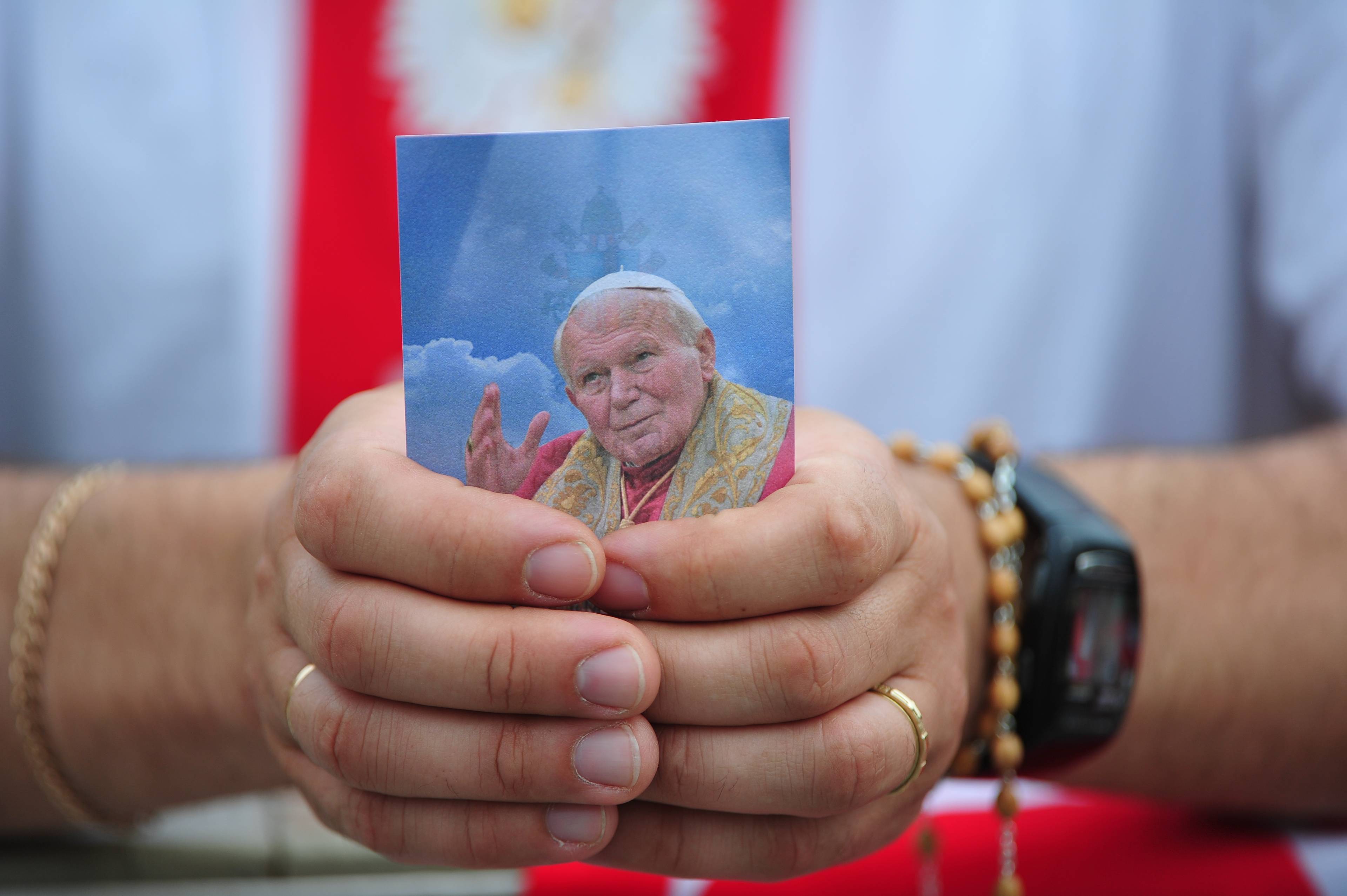 A Pilgrim holds a photo of the late Pope John Paul II while attending a mass of thanksgiving led by Vatican Secretary of State Tarcisio Bertone in Saint Peter's Square  in the Vatican on May 2, 2011. A giant banner bearing a smiling portrait of the charismatic Polish pope was unveiled over the facade of Saint Peter's Basilica Sunday after Benedict pronounced the formula of beatification just six years after John Paul's death. AFP PHOTO/ALBERTO PIZZOLI (Photo by ALBERTO PIZZOLI / AFP)