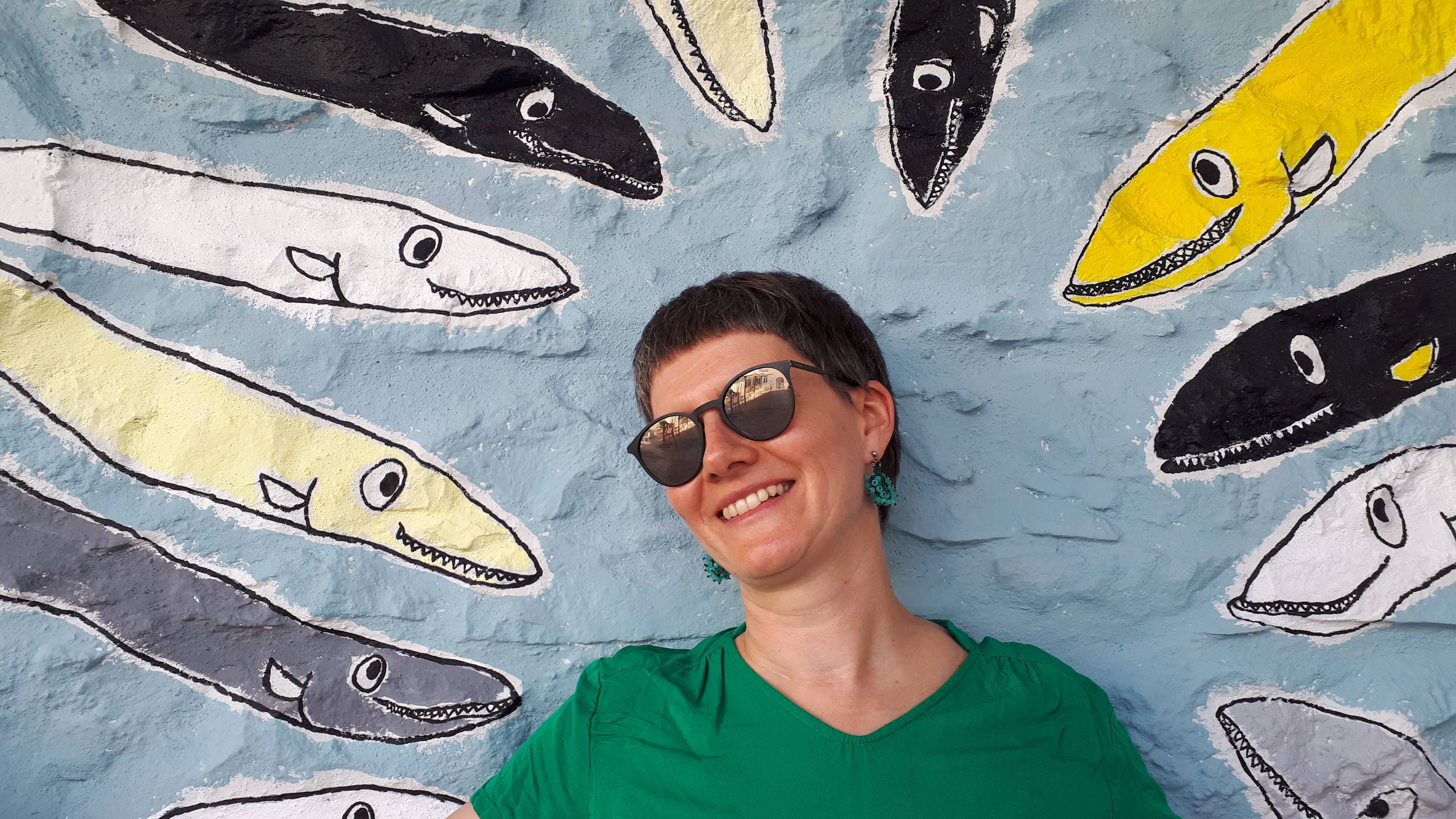 Portret kobiety w ciemnych okularach na tle graffiti z rybami