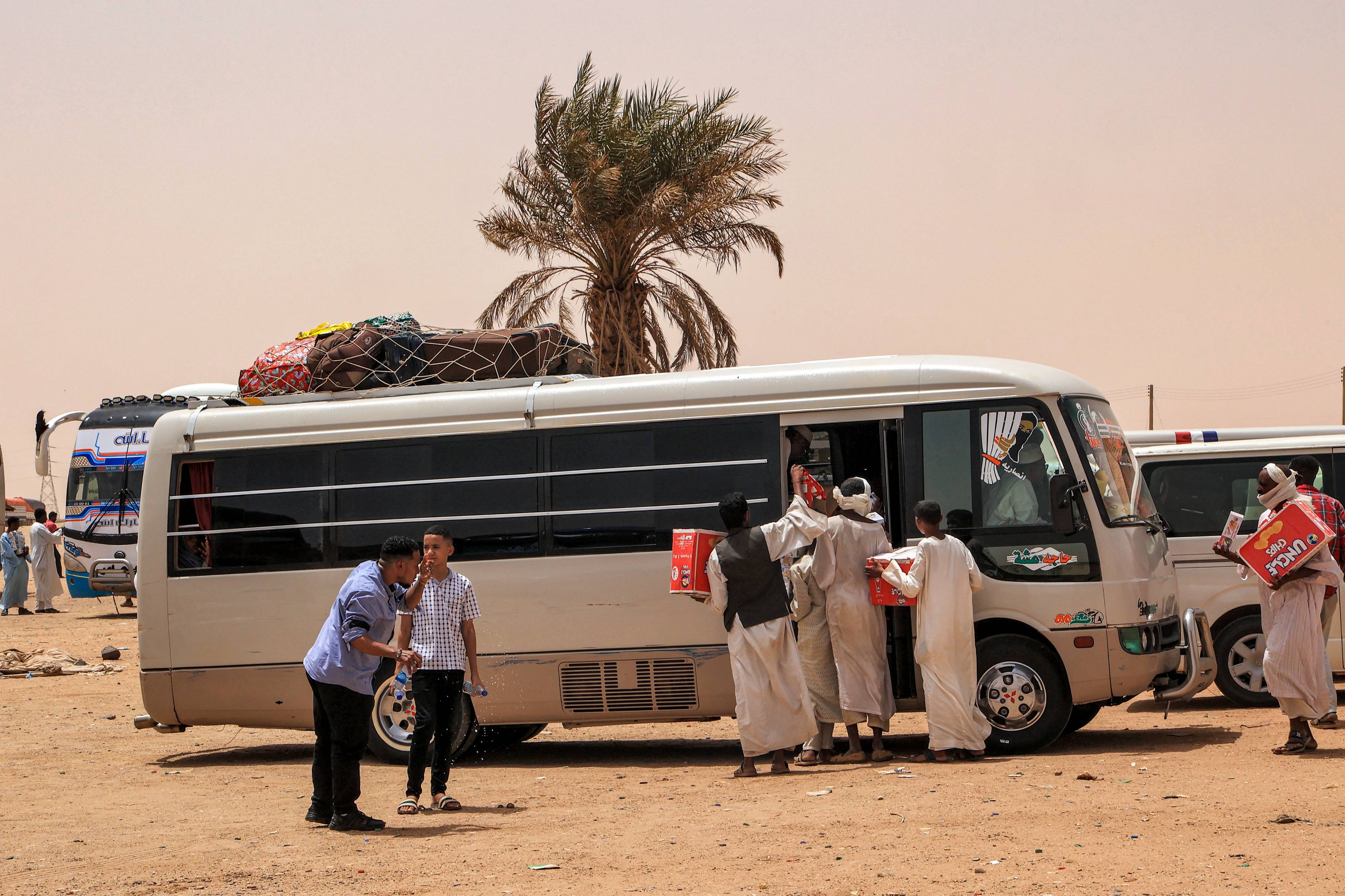 Wewnętrzni uchodźcy w Sudanie. 25 kwietnia 2023 r. akwizytorzy oferują przekąski na sprzedaż ludziom wsiadającym do autobusu pasażerskiego na przystanku Multaga w pobliżu Ganetti w północnym stanie Sudanu, około 300 kilometrów na północny zachód od stolicy