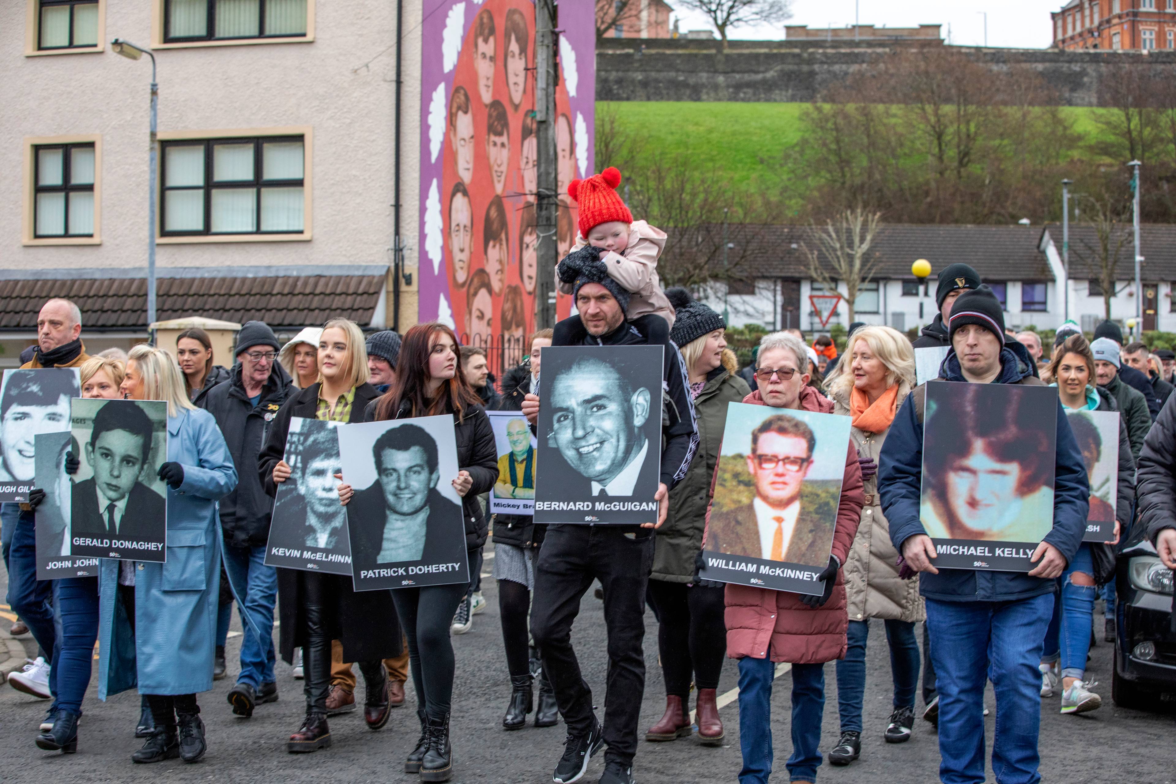 Family members carry photographs of those killed on Bloody Sunday at a memorial march to the Bogside for a wreath laying ceremony at a monument to those killed on the day, in Londonderry (Derry), Northern Ireland, on January 30, 2022, on the 50th anniversary of the Bloody Sunday shootings. - The Northern Irish city of Londonderry began commemorations Sunday of one of the darkest days in modern UK history when, 50 years ago, British troops without provocation killed 13 unarmed civil rights protesters. (Photo by PAUL FAITH / AFP)
