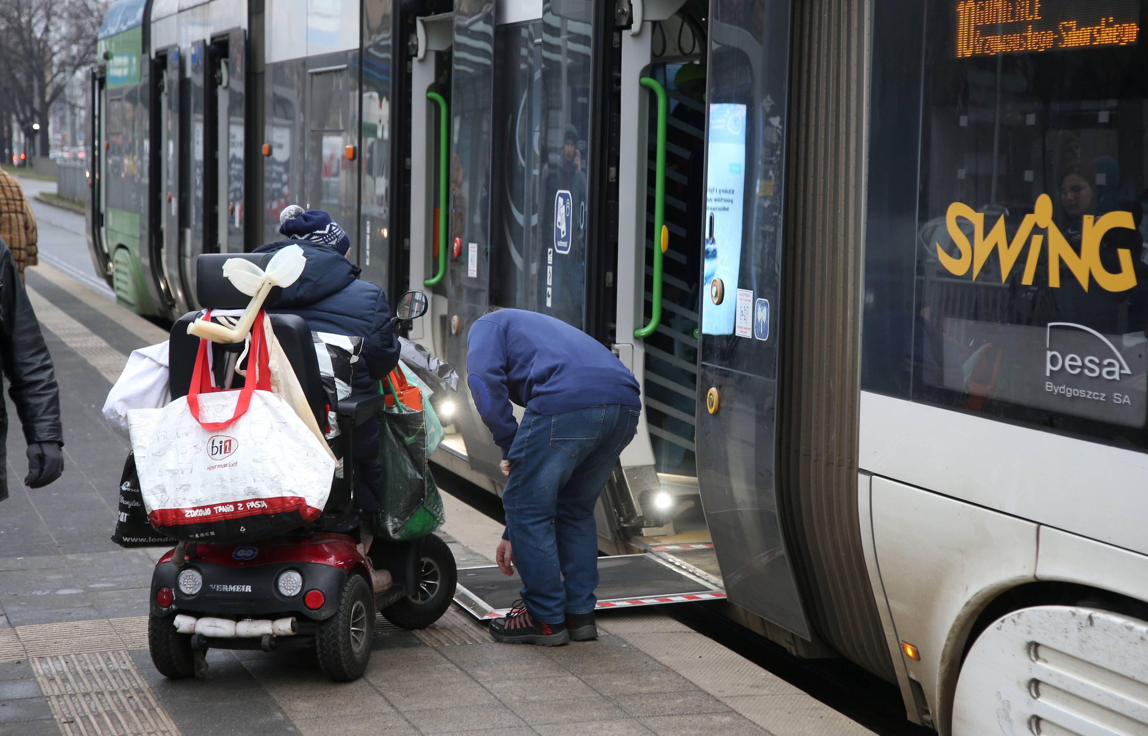 Człowiek na elektrycznym wózku wjeżdża do niskopodłogowego tramwaju