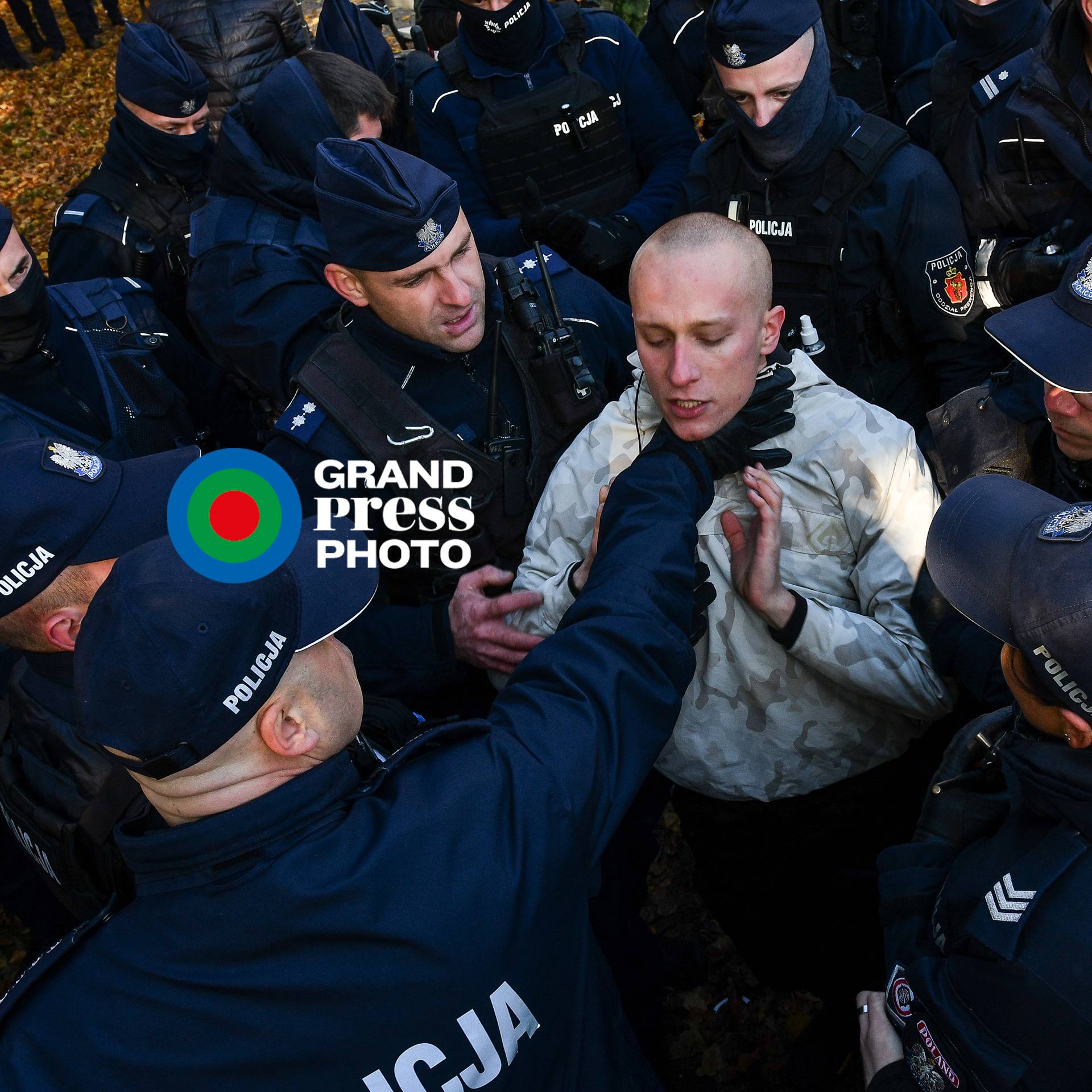 Policjant chwyta za gardło protestującego, otoczonego przez innych policjantów