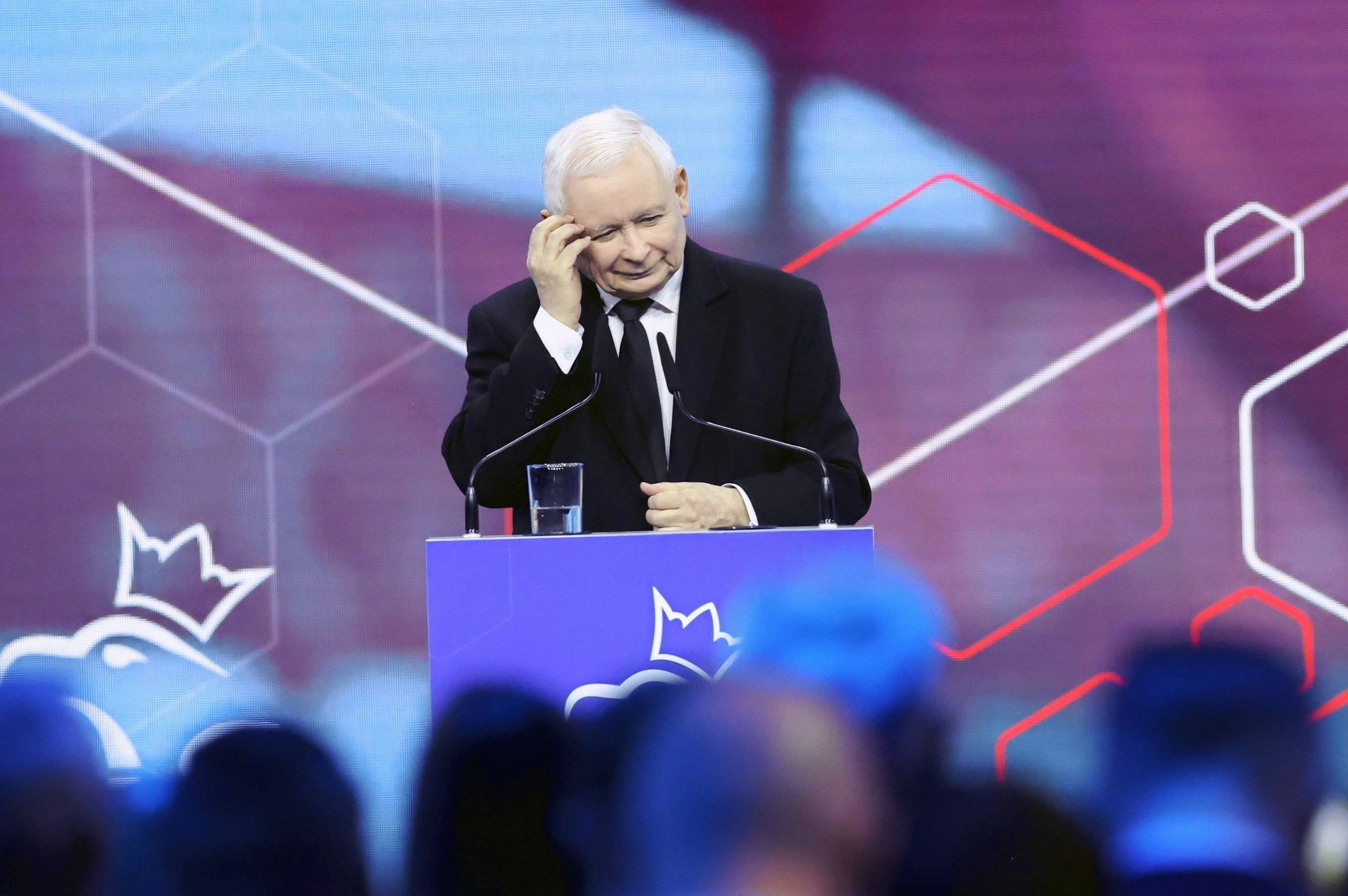 Jarosław Kaczyński stoi za mównicą i drapie się po głowie