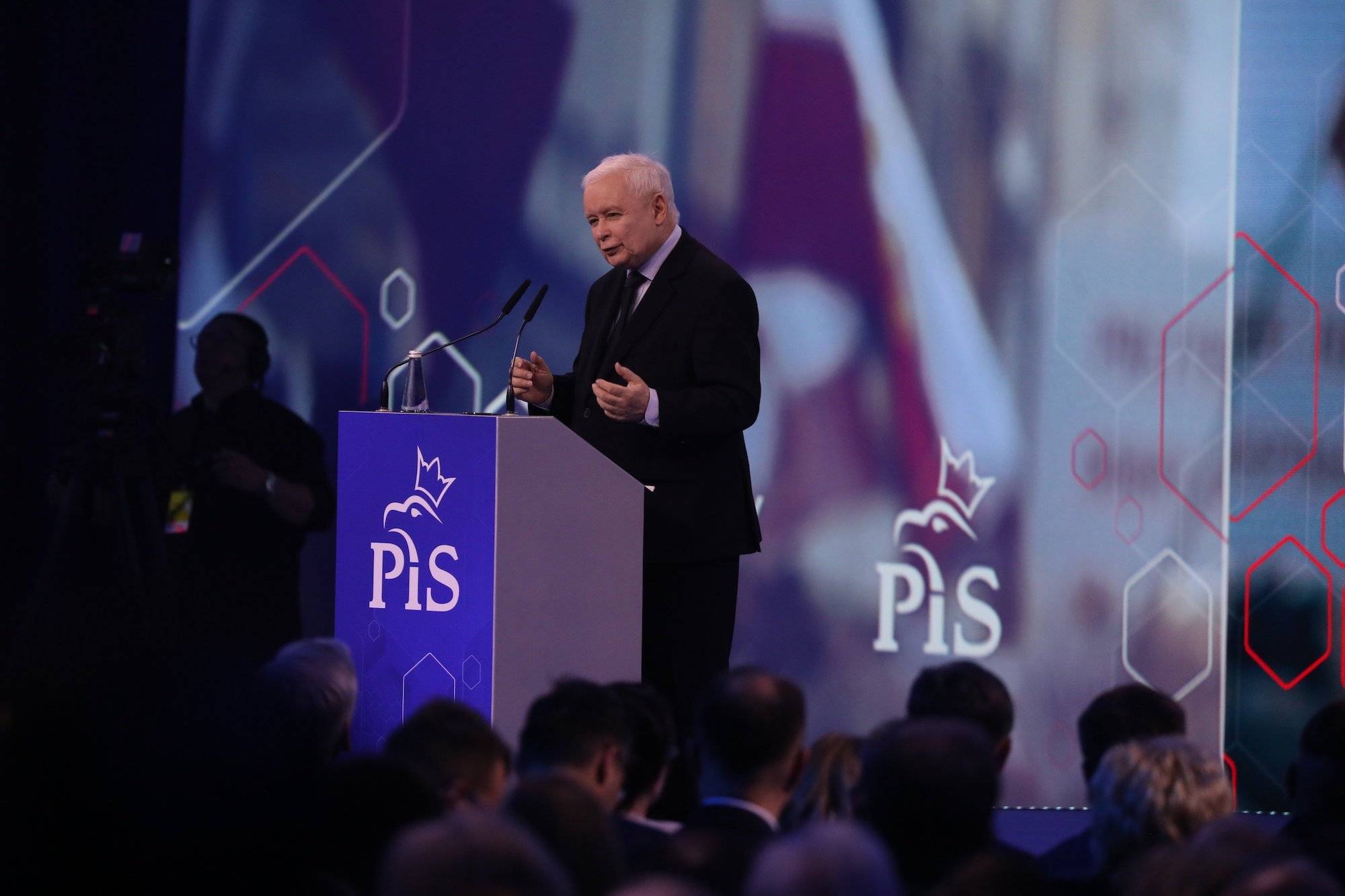 Jarosław Kaczyński podczas konwencji PiS w Warszawie. Stoi przy podium z logo PiS i przemawia do publiczności na tle dużego ledowego ekranu.