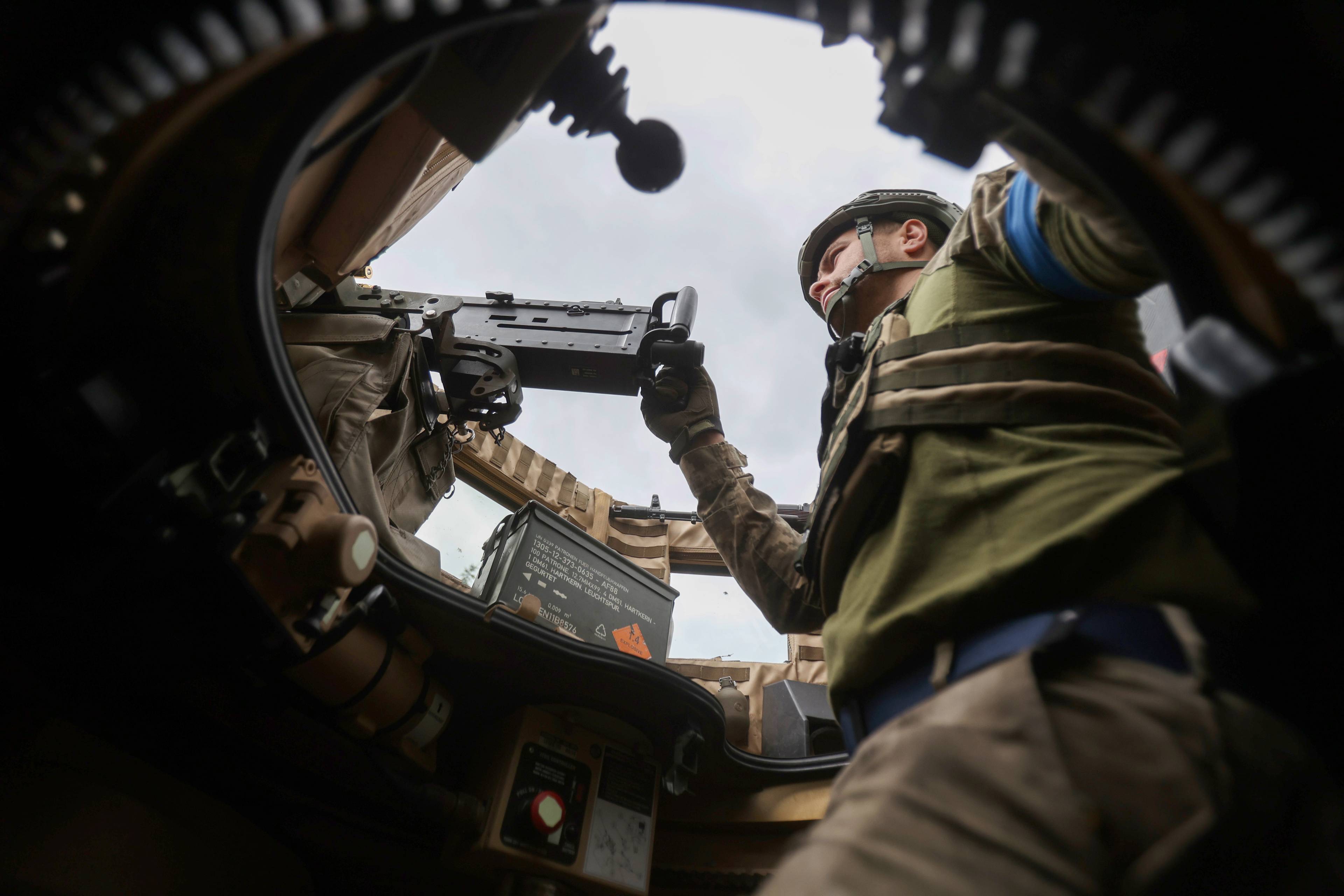 ujęcie z wnętrza czołgu, żołnierz obsługujący karabin maszynowy wygląda z otwartego włazu