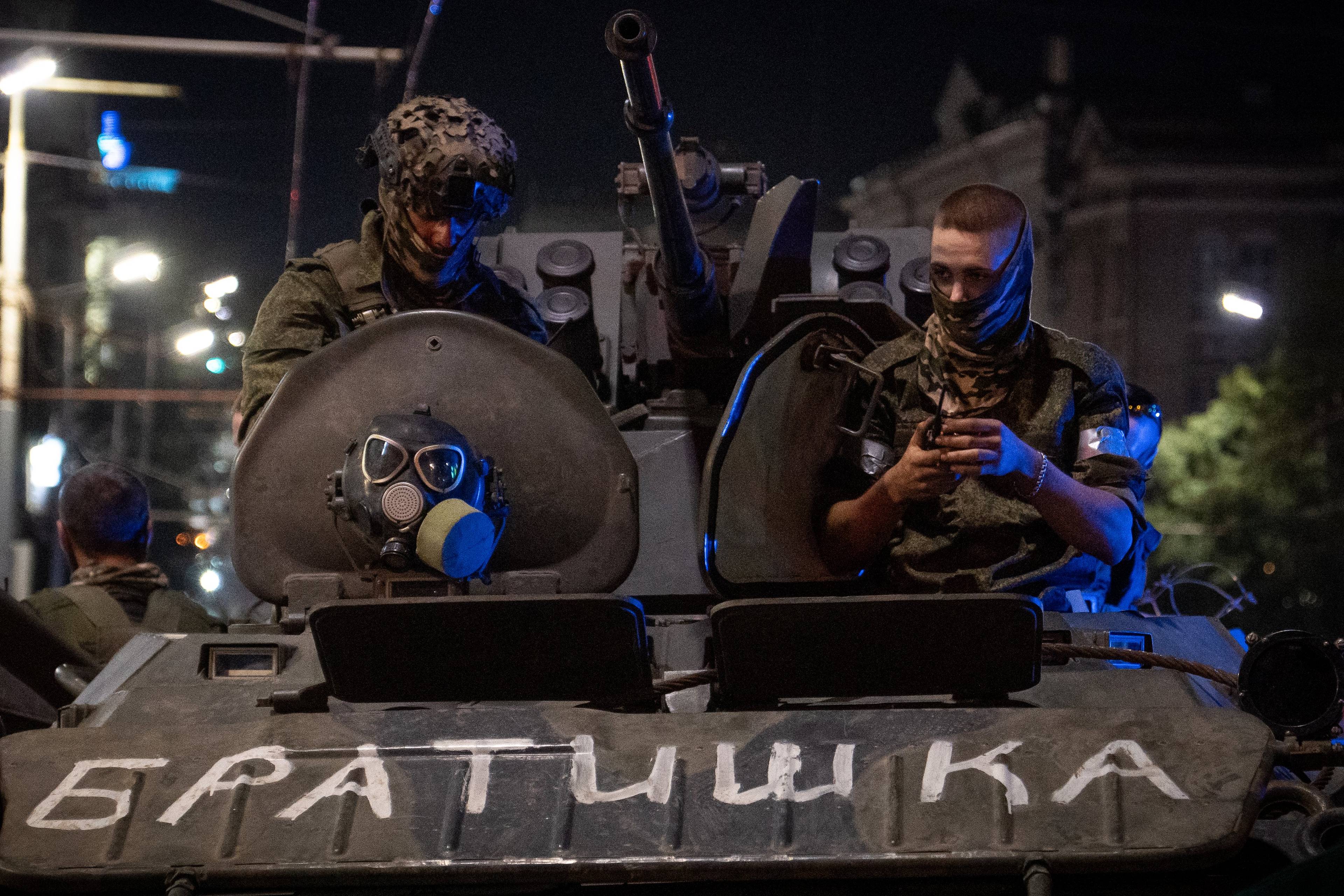 żołnierze w rynsztunku bojowym wyglądają z czołgu