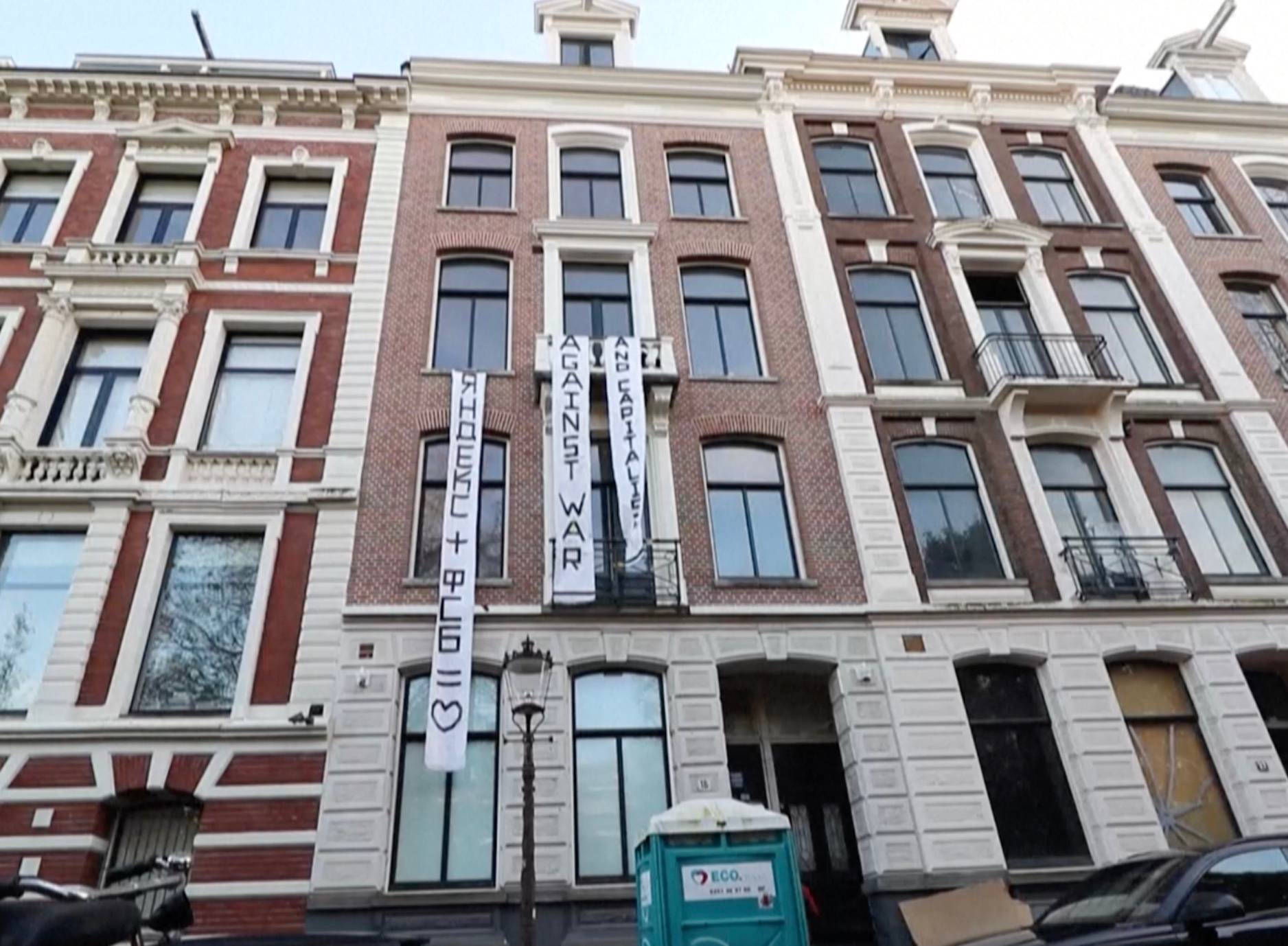 Kamienice w Amsterdamie, na jednej z nich pionowy transparent w j. rosyjskim: Yandex + FSB = znak serca. SŻlotersi z Amsterdamu zajęli kamienicę rosyjskiego oligarchy.