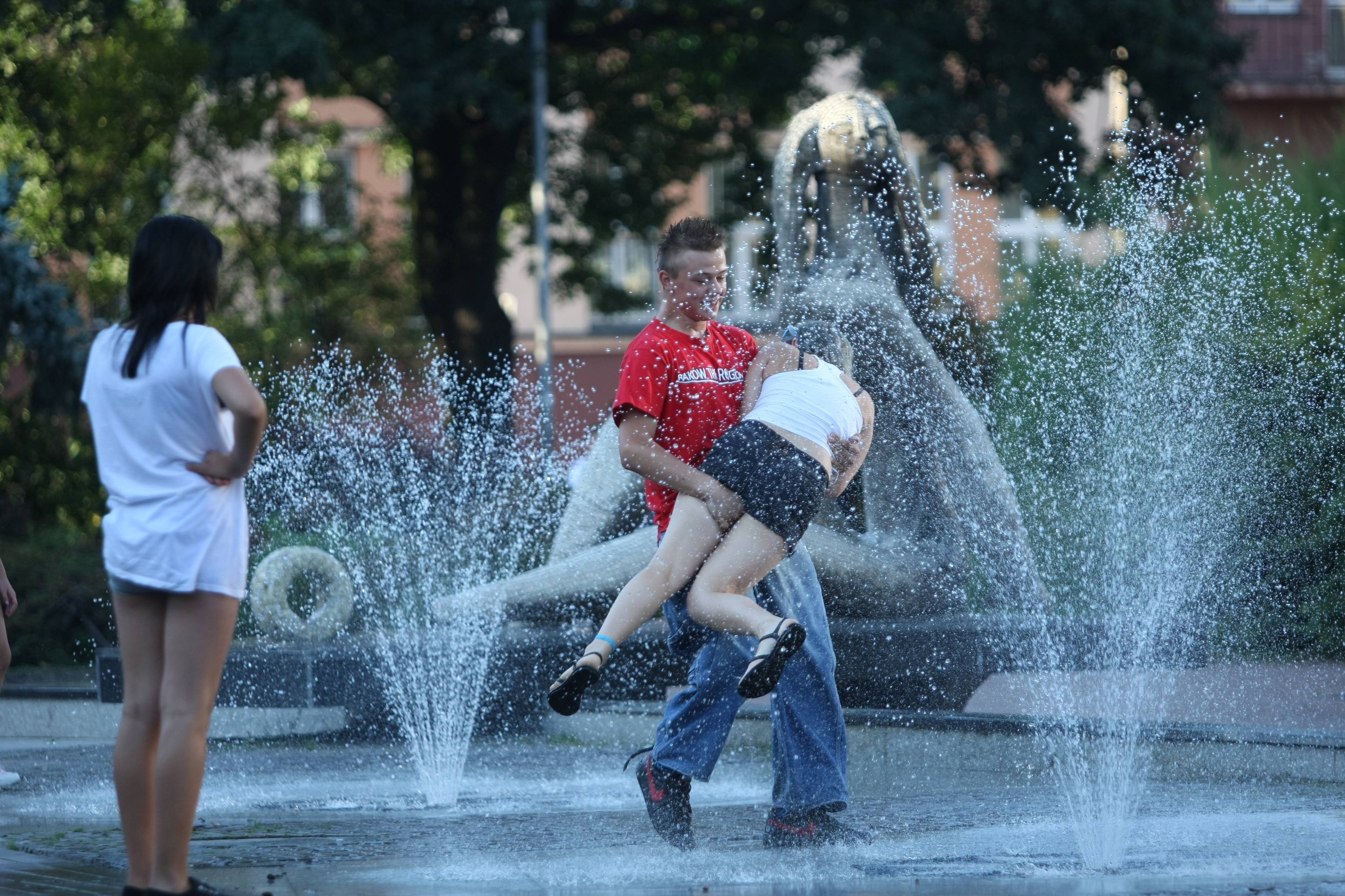 Chłopak i dziewczyna bawią się w fontannie